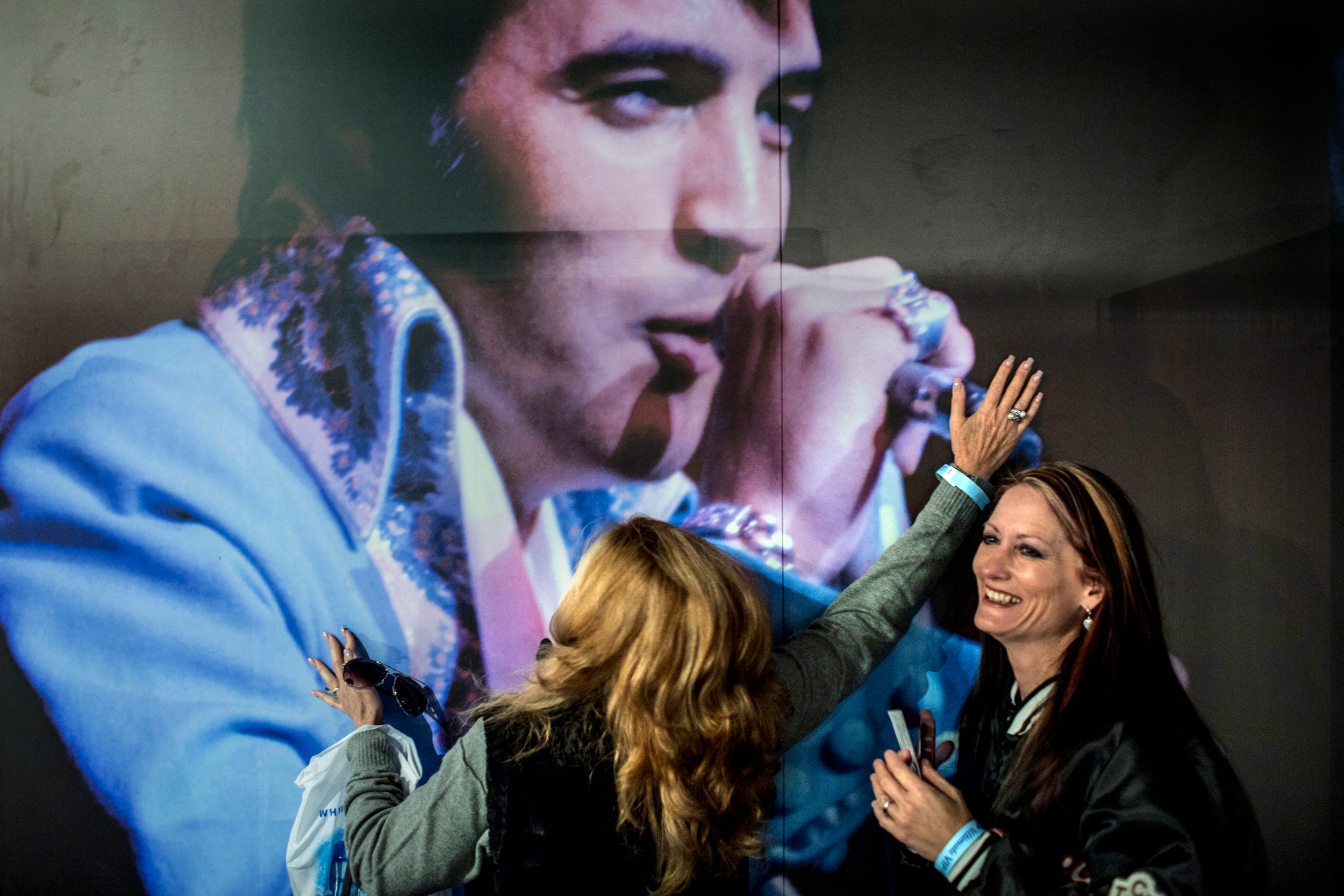 Shelley Dorazio, left, embraces a picture of Elvis Presley while Jenny Furr laughs inside the Elvis Presley's Memphis installation at Graceland.