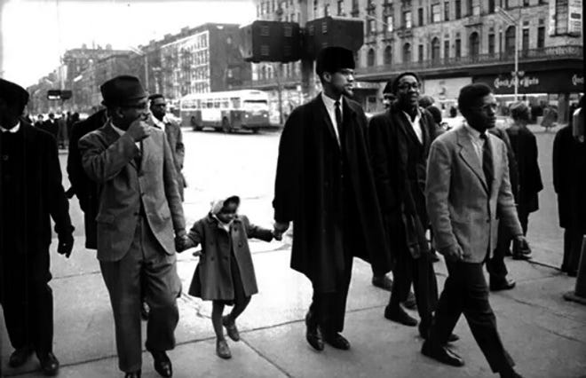 Malcolm X holds the hand of his daughter, Ilyasah Shabazz, as they walk down the street, undated photo.