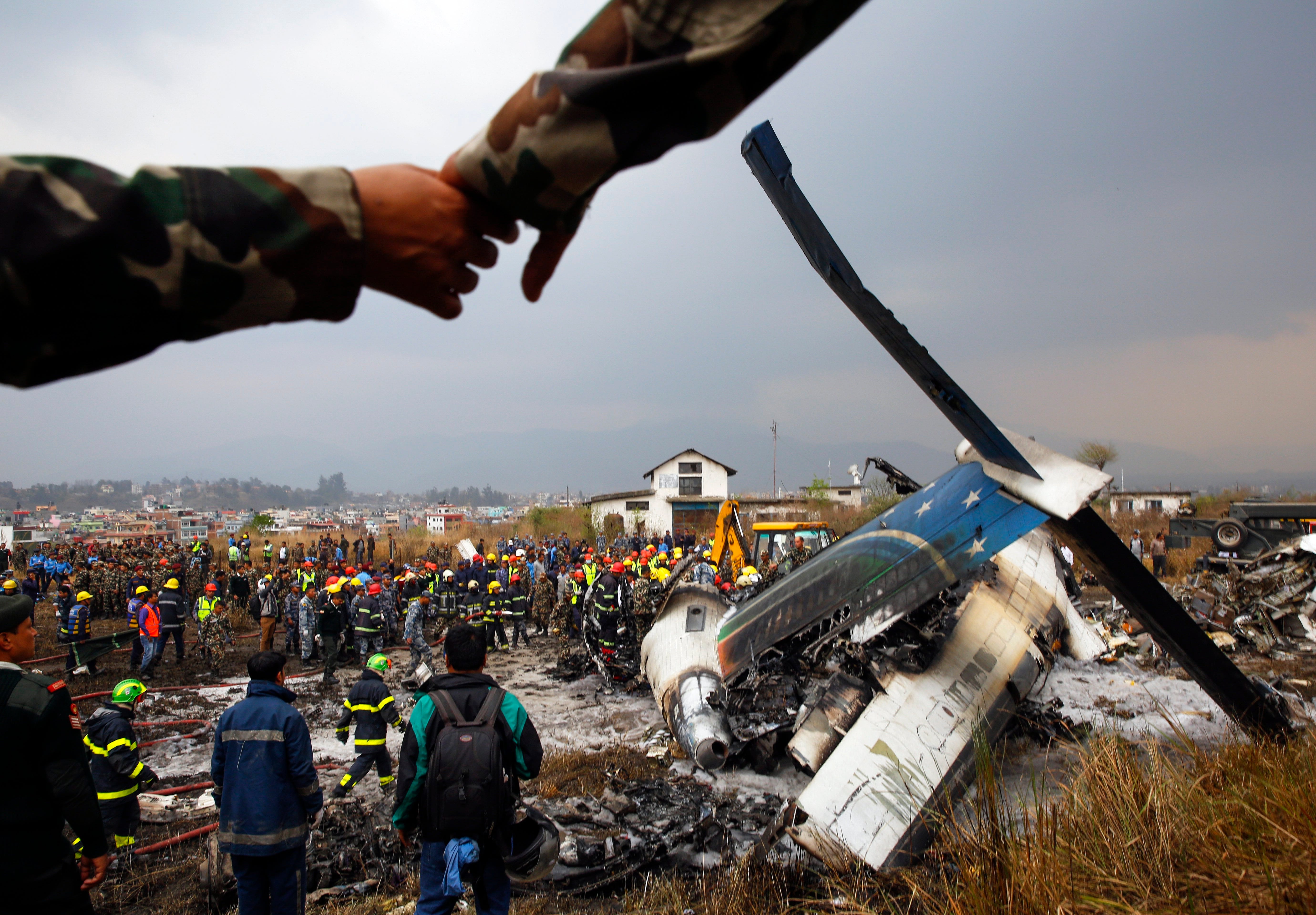 Rescue teams gather next to the wreckage of a plane that crashed at the main airport Tribhuvan International Airport in Kathmandu, Nepal. According to reports the plane crashed while landing and had 71 passengers and crew on board and at least 38 peo