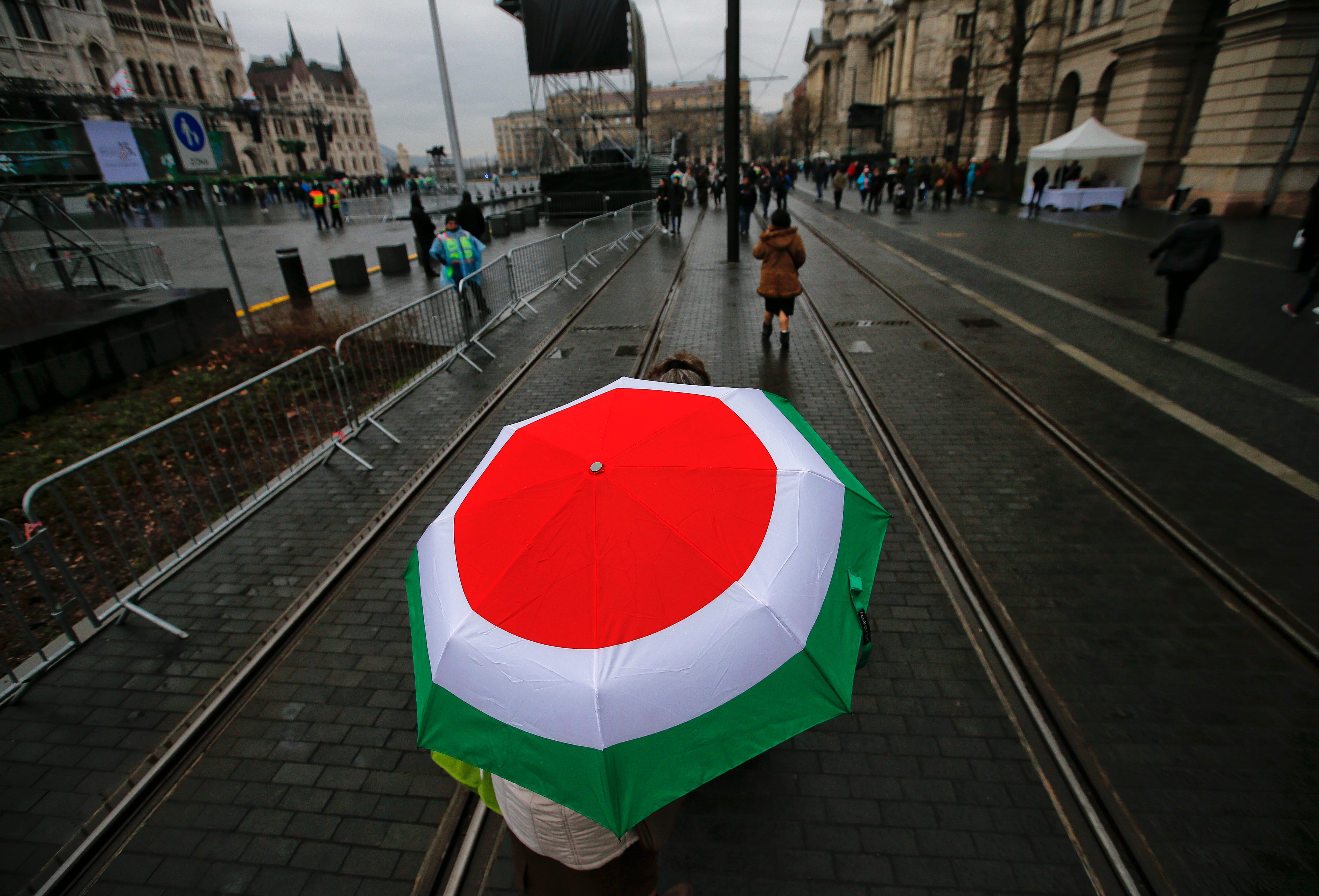 A supporter of Hungarian Prime Minister Viktor Orban walks under an umbrella in Hungary's national flag colors outside the Parliament building in Budapest. Hungary is celebrating their national holiday, the 170th anniversary of the outbreak of the 18