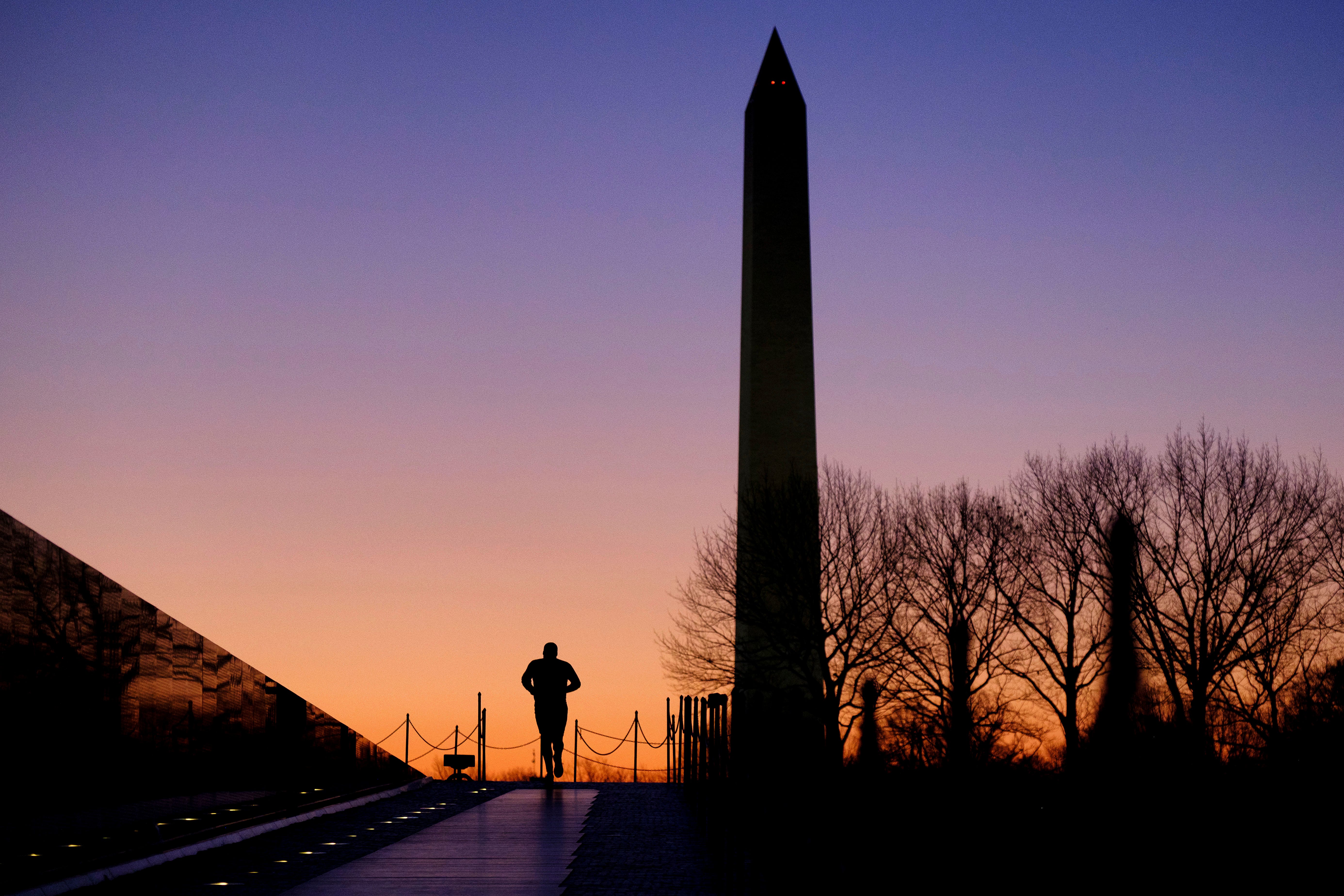 An early morning runner heads past the Vietnam War Memorial towards the Washington Monument at daybreak in Washington.