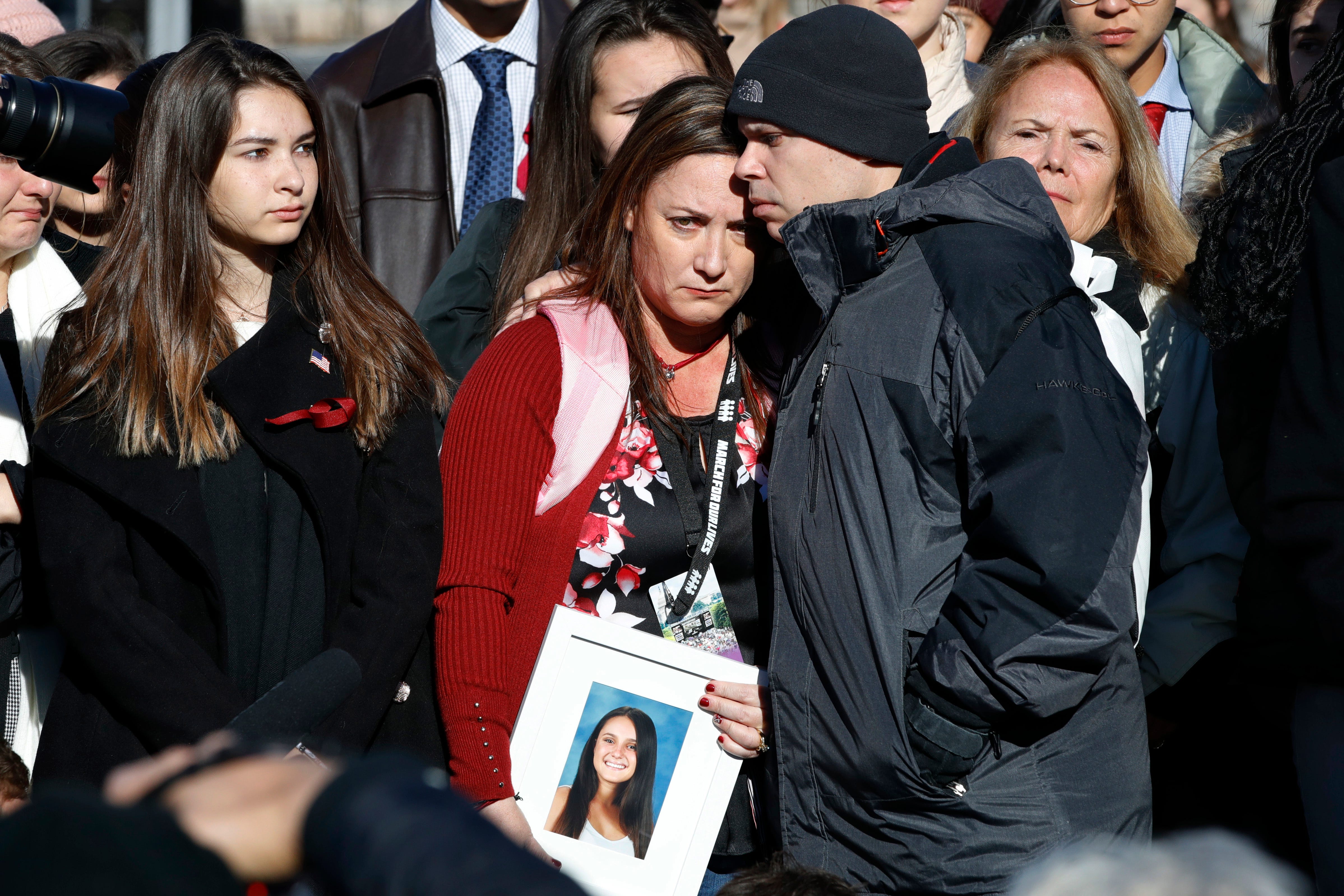 Lori Alhadeff, center, is comforted by her husband Ilan Alhadeff, as she holds a photograph of their daughter, Alyssa Alhadeff, 14, who was killed in the shootings at Marjory Stoneman Douglas High School, while they attend a news conference on gun vi