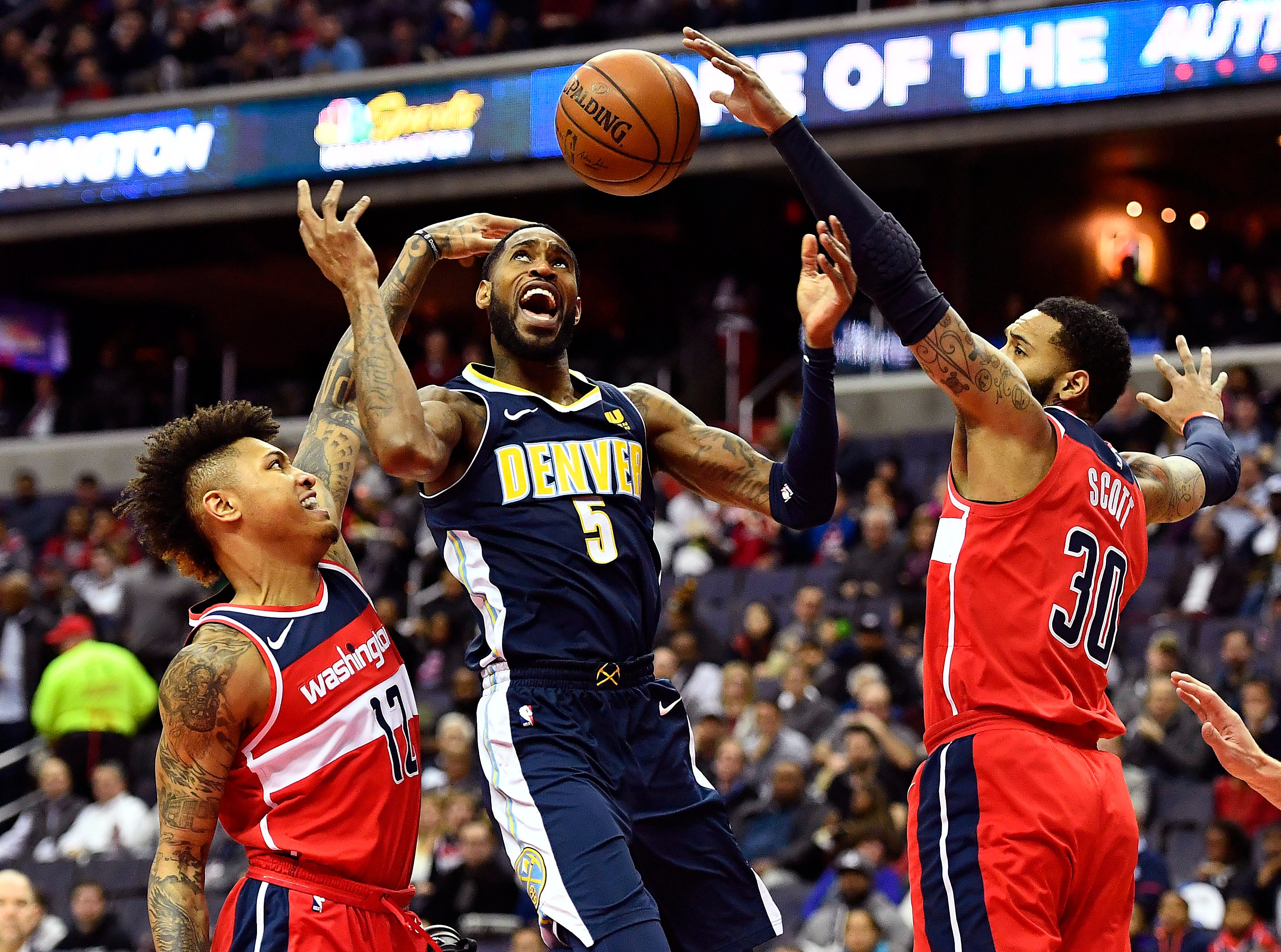 Washington Wizards forward Kelly Oubre Jr. (12) knocks the ball away from Denver Nuggets forward Will Barton (5) as Washington Wizards guard Tomas Satoransky (31) looks on during the first half at Capital One Arena.