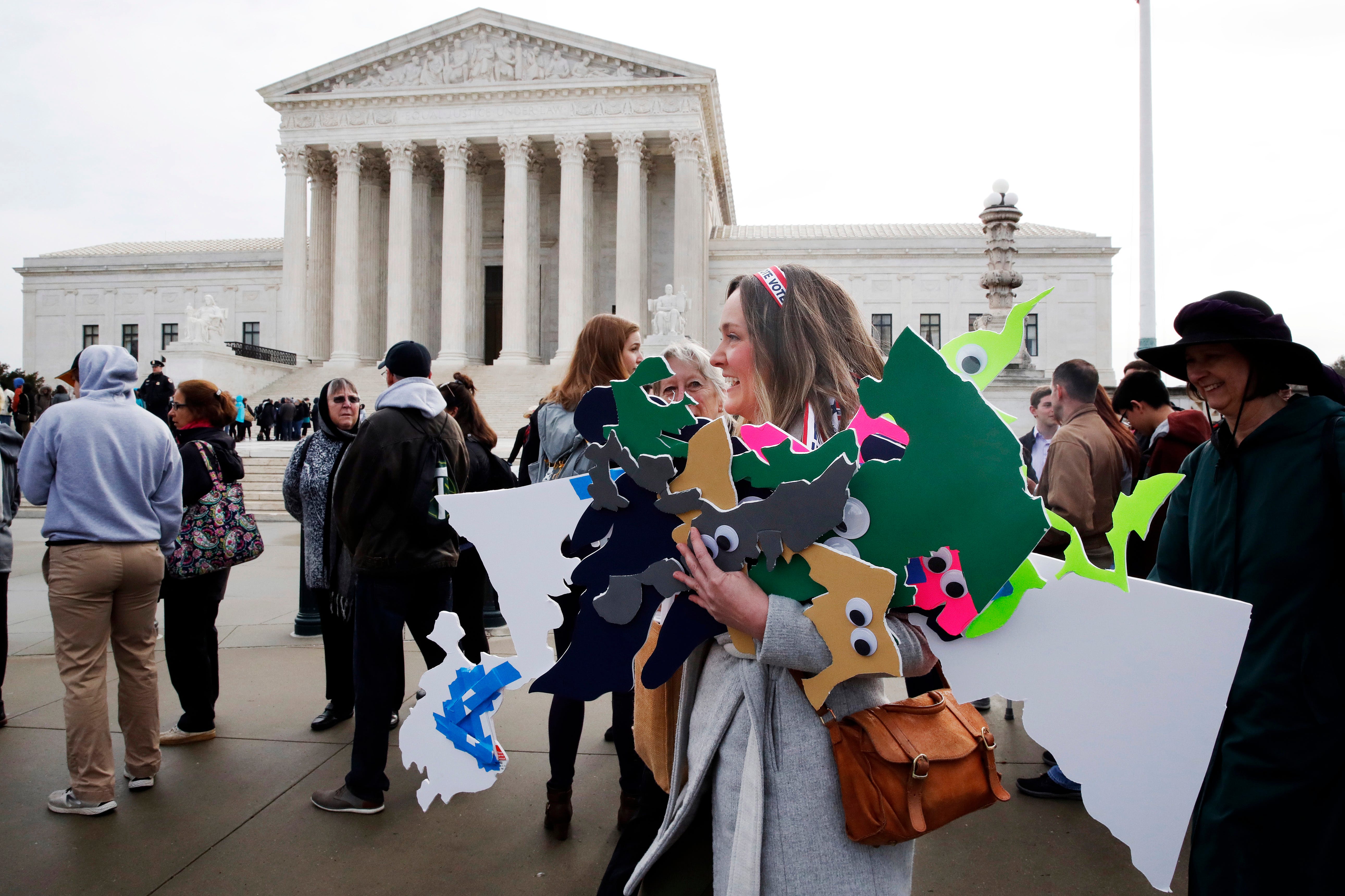 Ashley Oleson, with the League of Women Voters of Maryland, carries signs of Maryland's districts, as nonpartisan groups against gerrymandering protest in front of the Supreme Court, March 28, 2018, in Washington where the court will hear arguments o