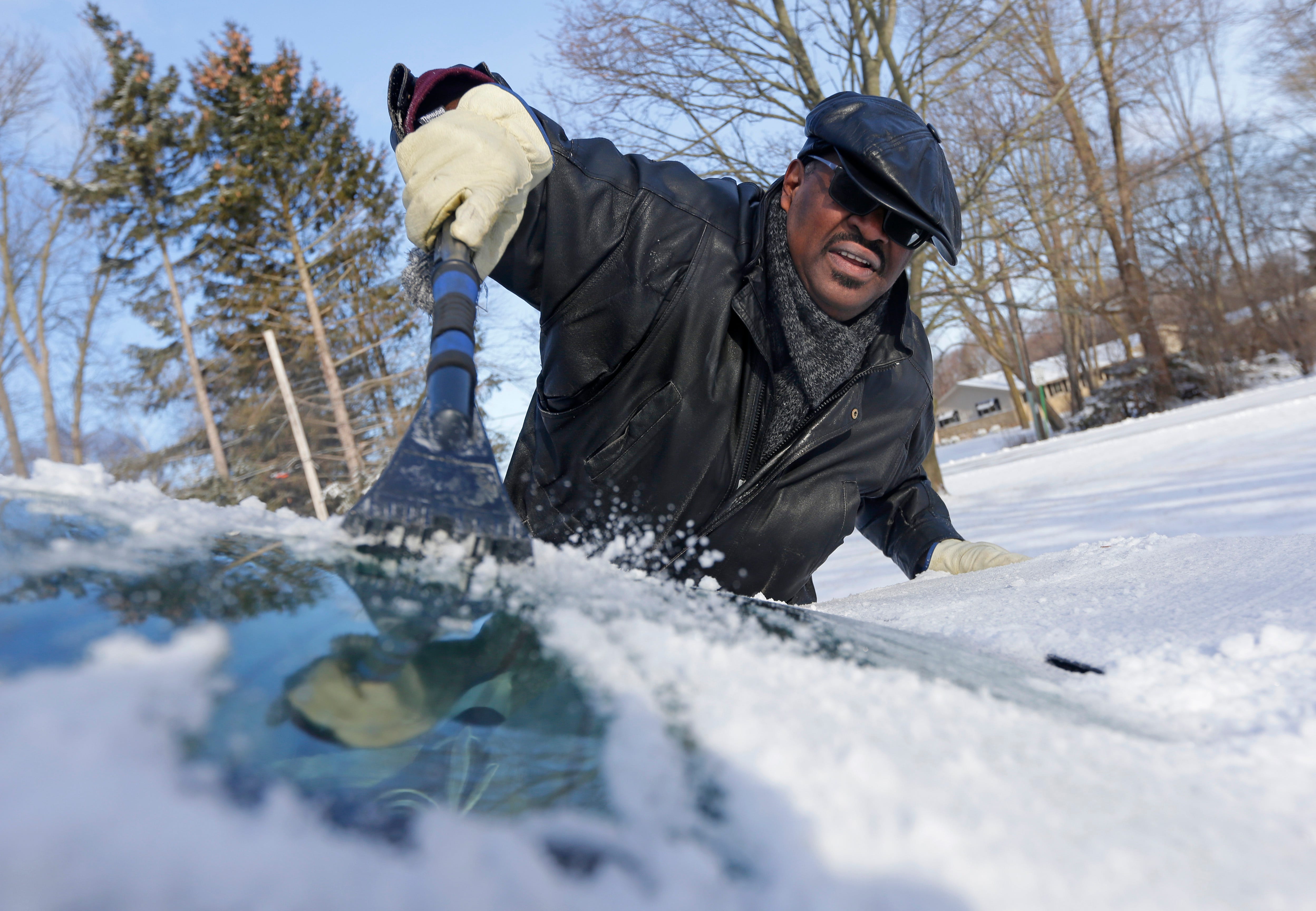 Thomas Prentice scrapes snow and ice off his car ion Milwaukee Wis. as a spring snowstorm dropped a couple of inches of snow on the region.