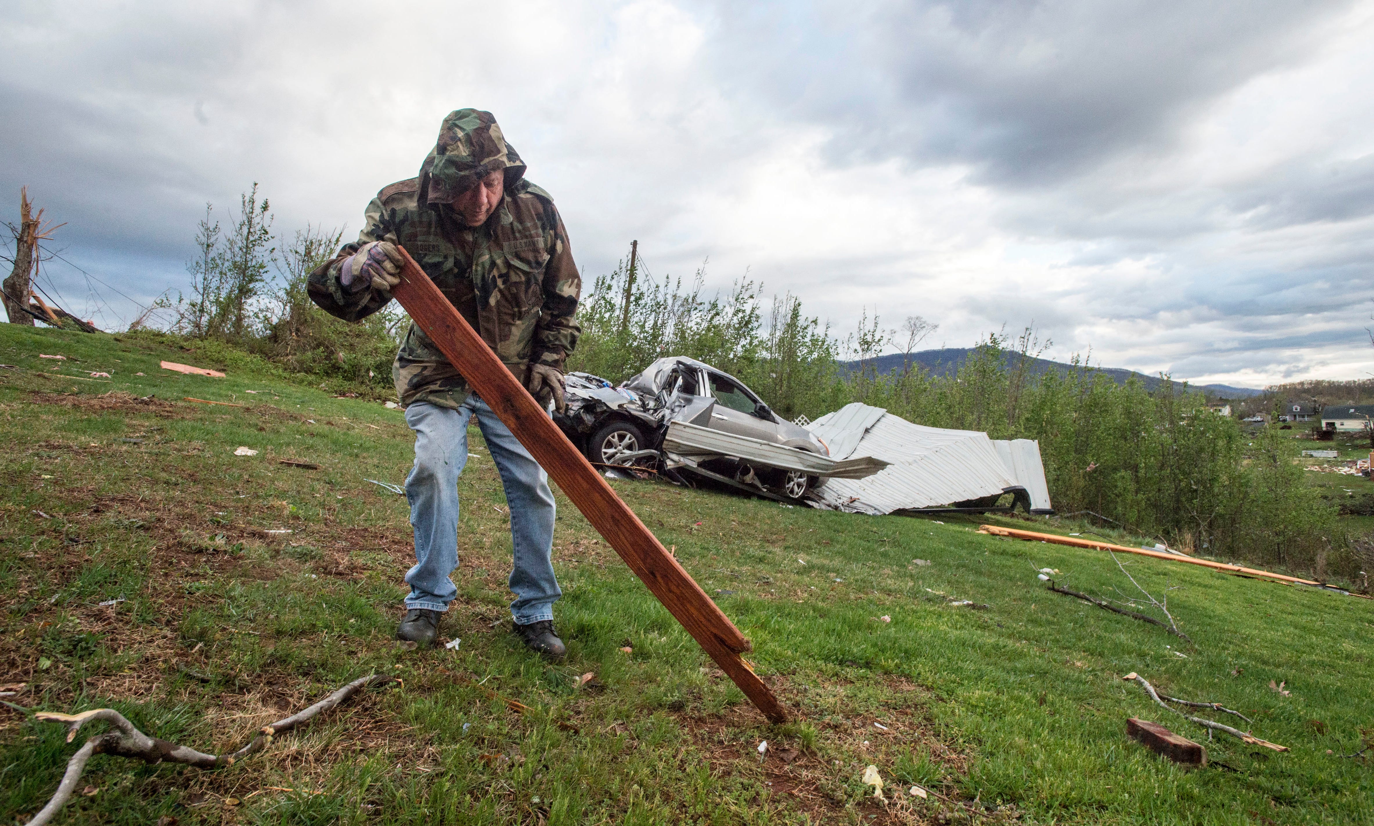David Neighbors picks up debris after a storm on Monday, April 16, 2018, in Elon, Va.  Wild weather continued to pound much of the eastern U.S. on Monday morning, with flood watches and warnings in place across several states, all the way from West V