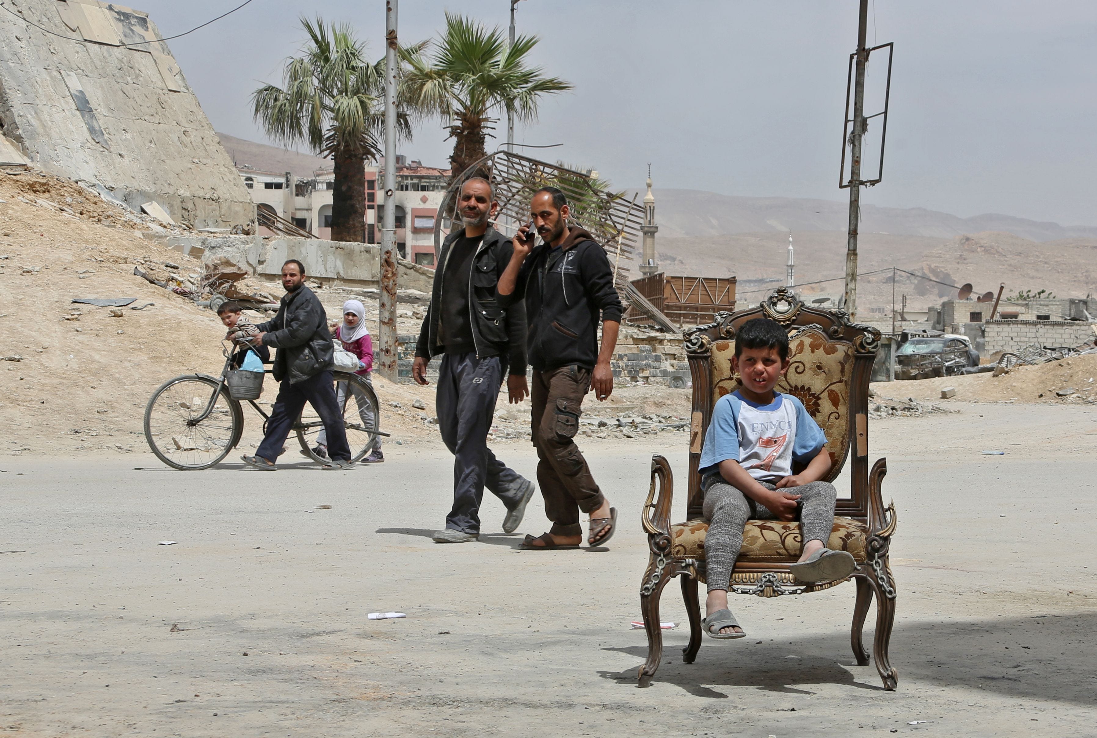 Civilians walk in the former rebel Syrian town of Douma on the outskirts of Damascus on April 17, 2018, after the Syrian army declared that all anti-regime forces have left Eastern Ghouta, following a blistering two month offensive on the rebel encla