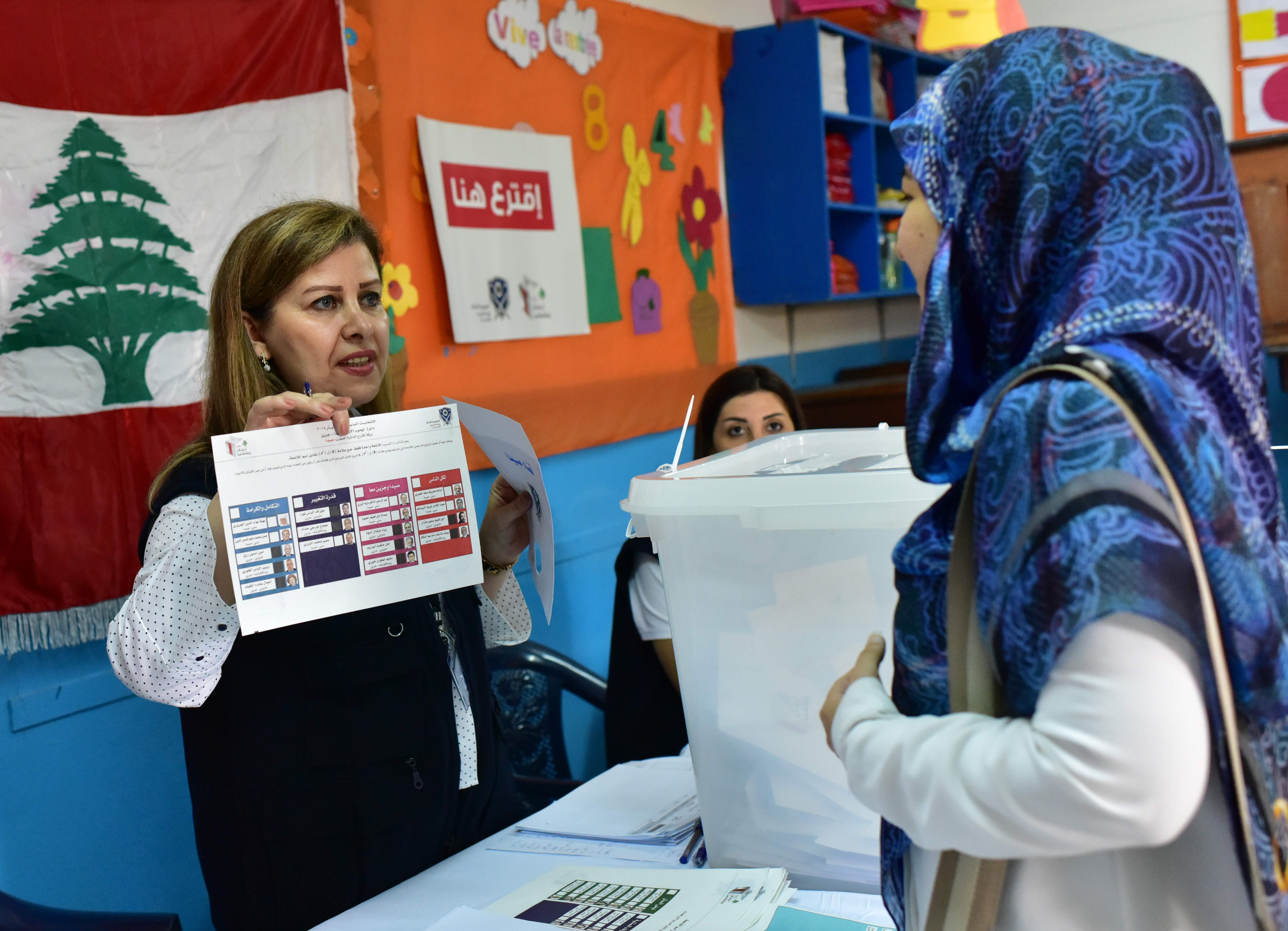 A pollisng station official explains the voting proceedure to a Lebanese national preparing to cast her ballot in the middle-eastern nations parliamentary election at a polling station set up at the Lebanese School in Abidjan on April 29, 2018.  Leban