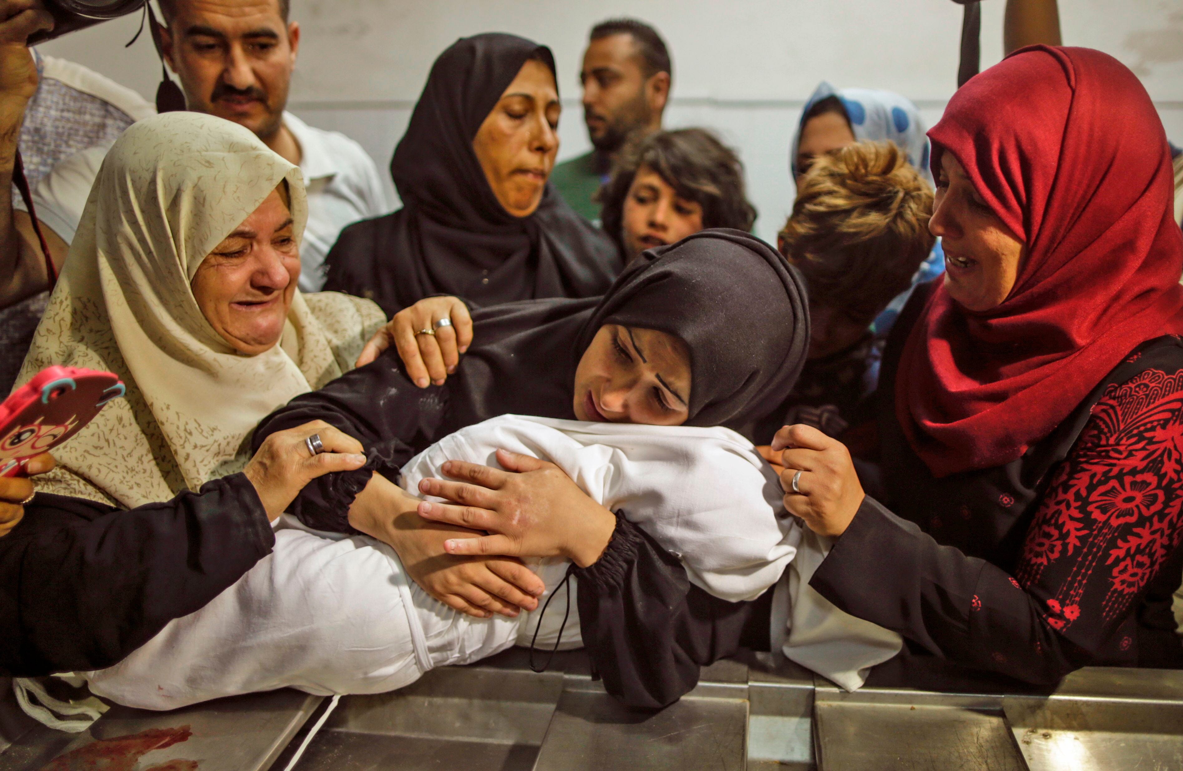 The mother of a Leila al-Ghandour (C), a Palestinian baby of 8 months who according to the Palestinian health ministry died of tear gas inhalation during clashes in East Gaza the previous day, holds her at the morgue of al-Shifa hospital in Gaza City