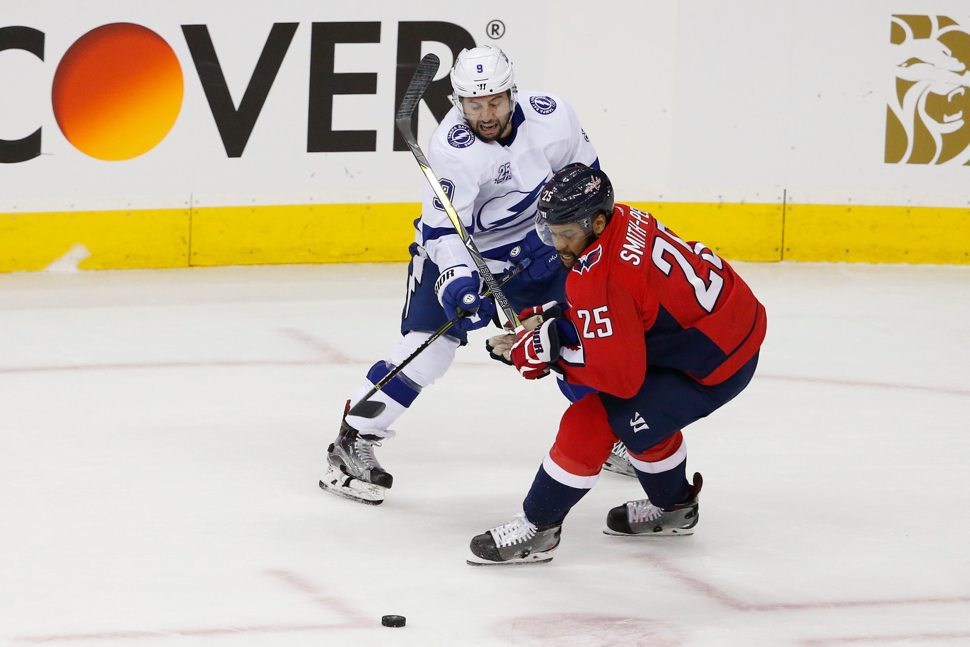 Tampa Bay Lightning center Tyler Johnson, left, passes the puck as Washington Capitals right wing Devante Smith-Pelly defends during the first period in game three of the Eastern Conference Final in the 2018 Stanley Cup Playoffs at Capital One Arena 