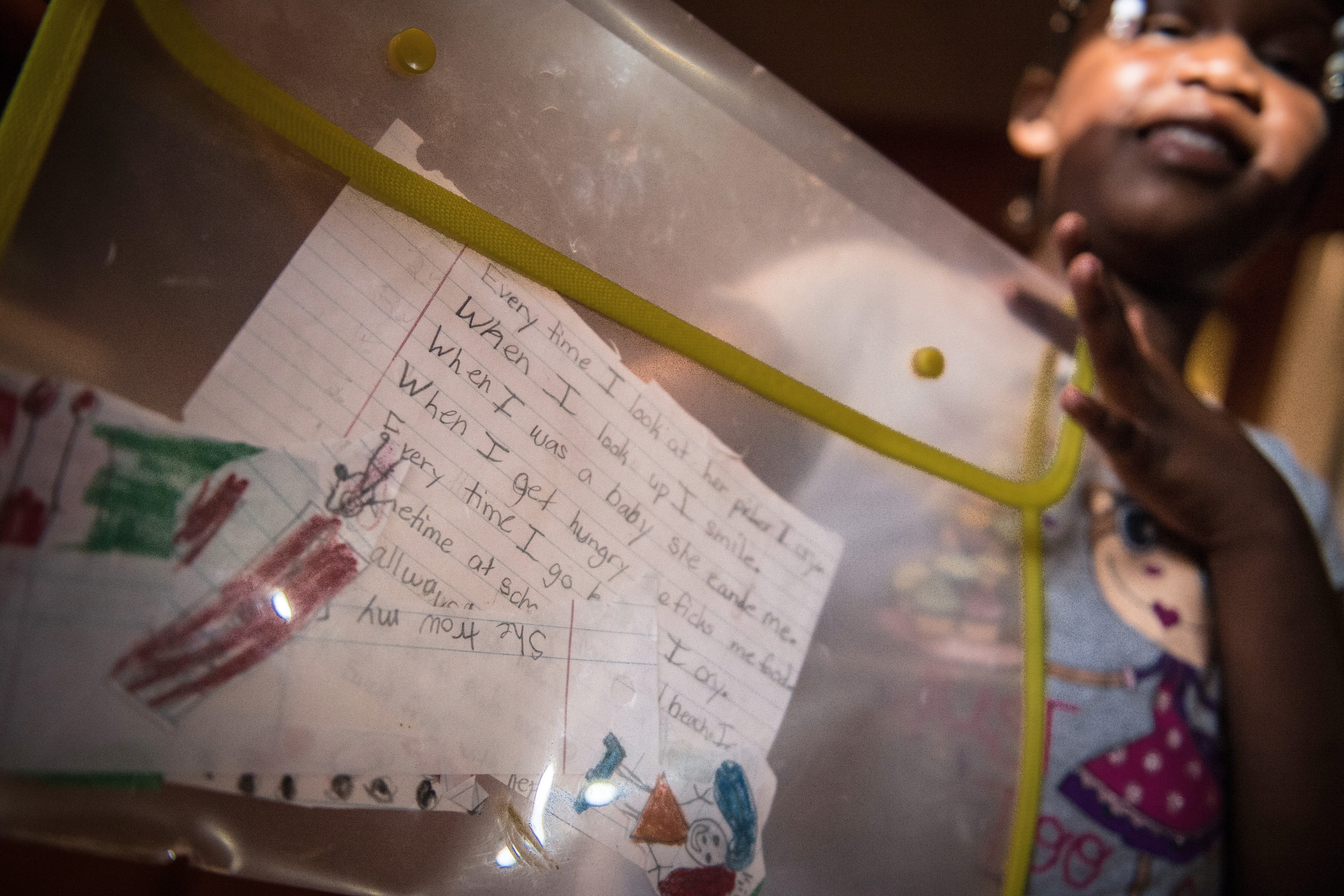 "When I look up, I smile," Shekinah Mention wrote about her mother YoLanda. She holds up some of her writing and drawings about her mother's life that she has saved at her home in Nesmith, South Carolina.