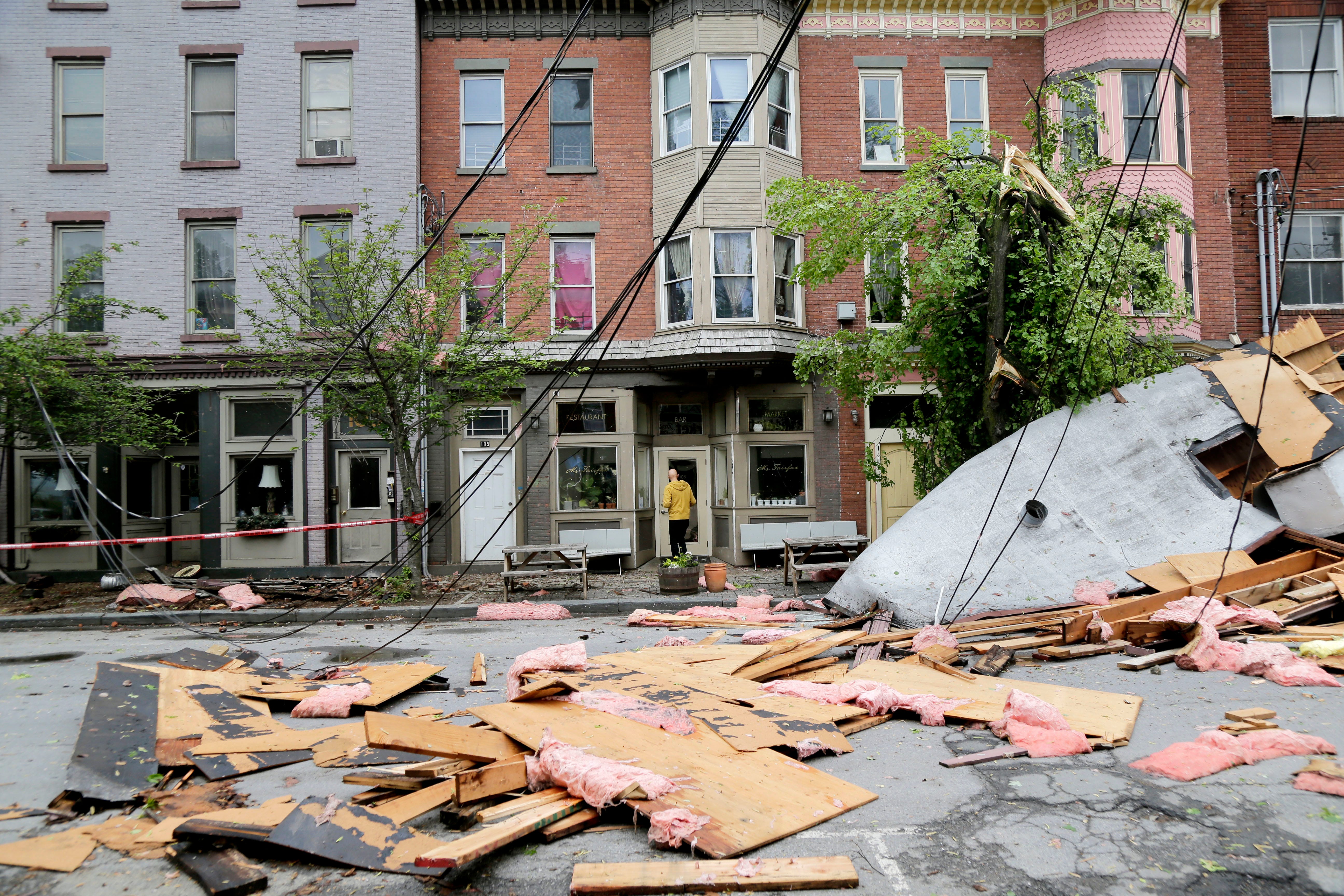 A man enters a building past debris caused by a storm in Newburgh, N.Y., May 16, 2018. Powerful storms pounded the Northeast on Tuesday with torrential rain and marble-sized hail, leaving thousands of homes and businesses without power.