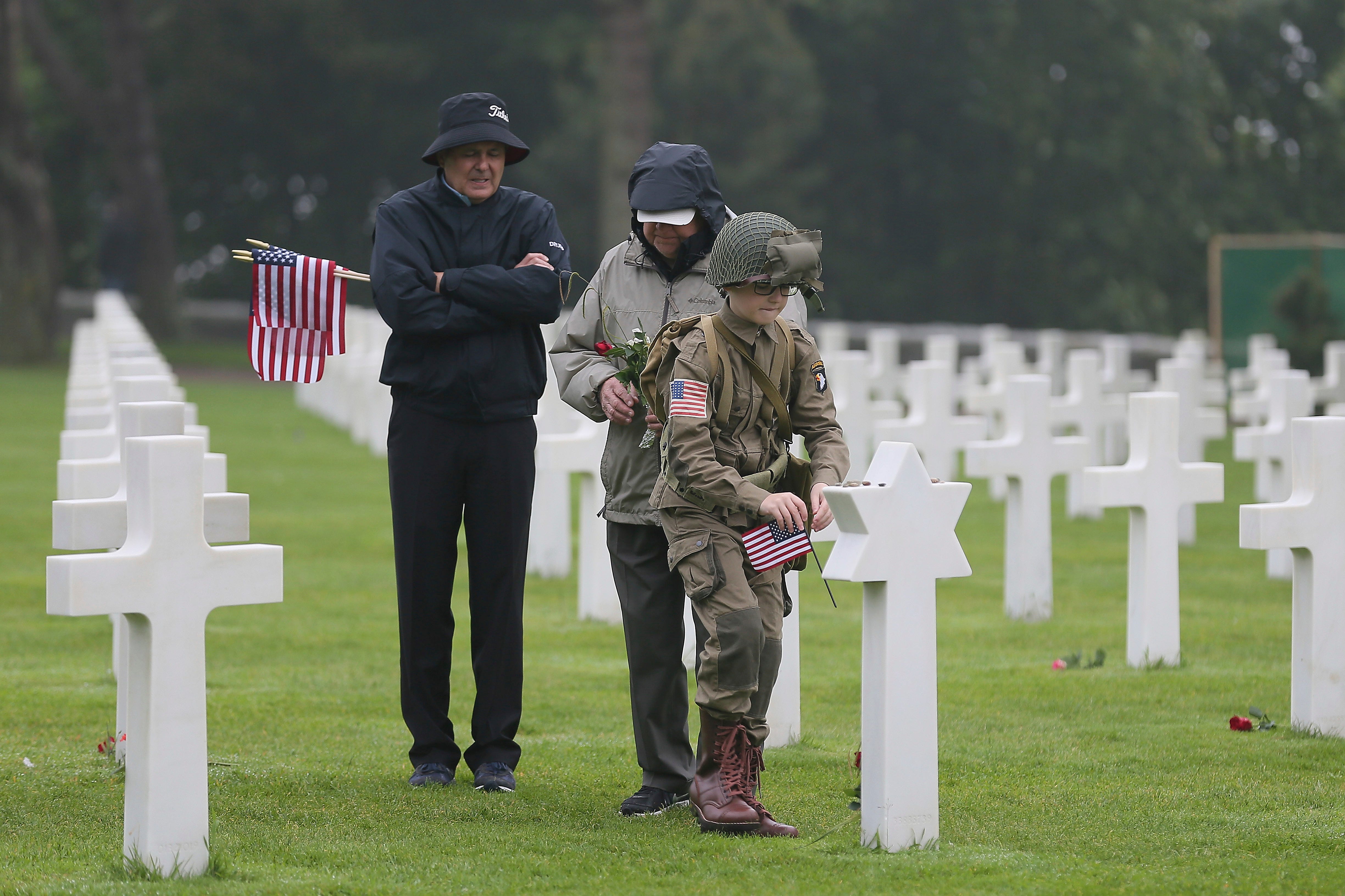 David Chamberlain, left, grandfather Charly Powers and his son Steve, from Atlanta, Georgia, pay their respect by putting down a US flag on the grave of a US soldier who died during World War II at the Colleville American military cemetery, in Collev