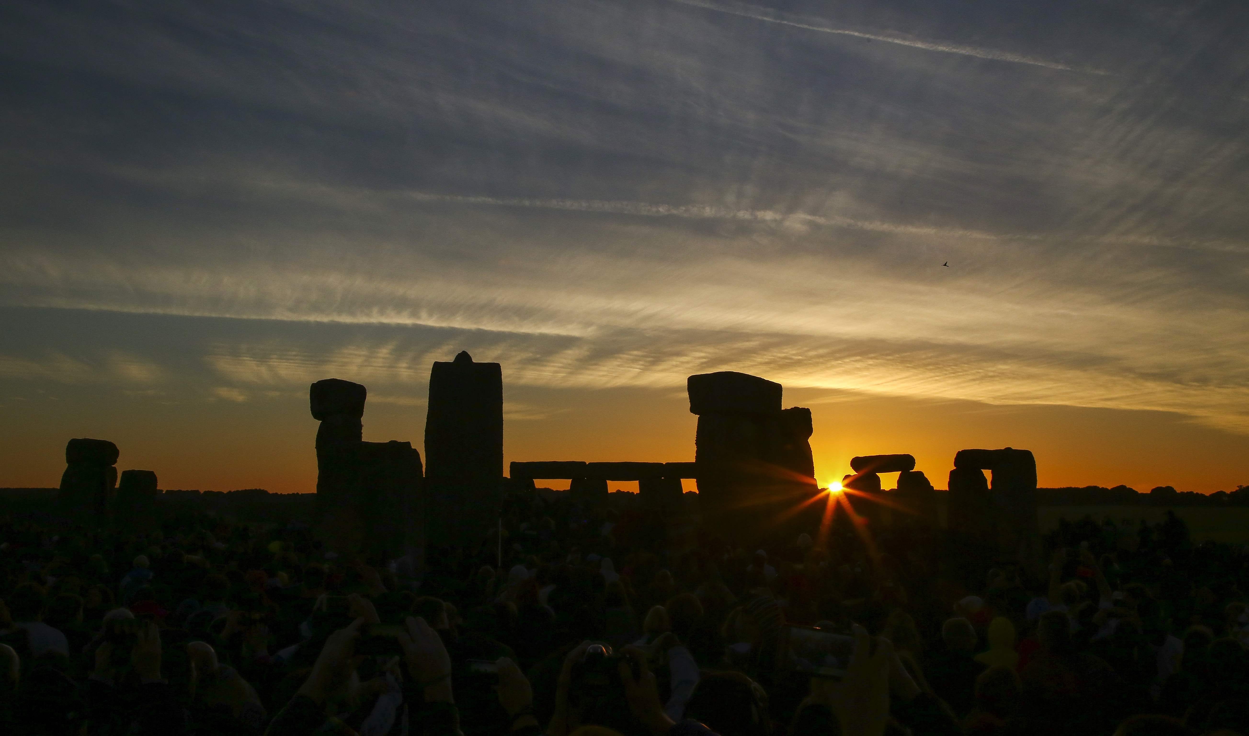 Revellers watch the sunrise as they celebrate the pagan festival of Summer Solstice at Stonehenge in Wiltshire,  England on June 21, 2018.  The festival, which dates back thousands of years, celebrates the longest day of the year when the sun is at it