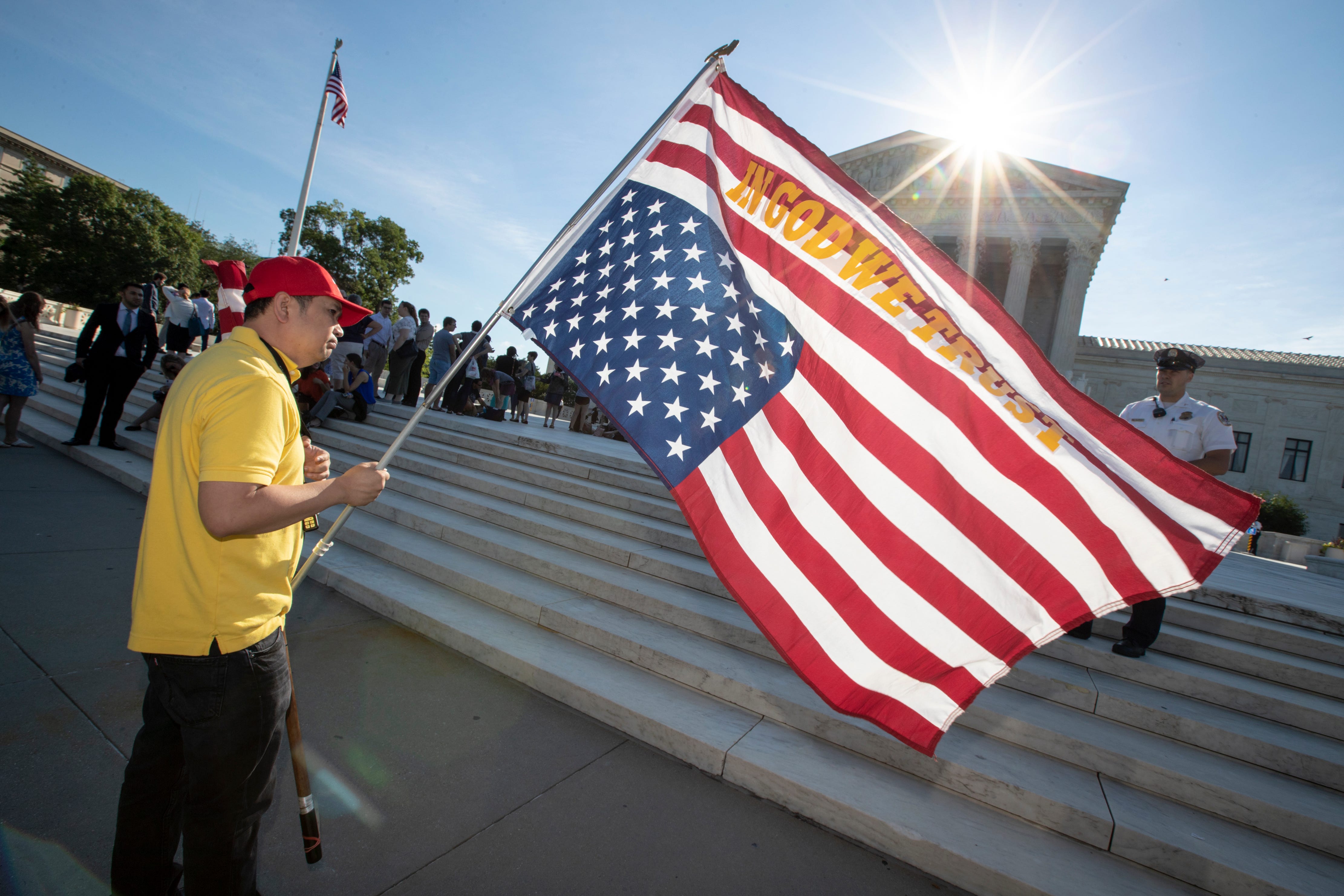 Penny Vu of Falls Church, Va., who immigrated to the United States from Vietnam 22 years ago, waves fa lag as he demonstrates in front of the Supreme Court early June 25, 2018. The justices are expected to hand down decisions today as the court's ter