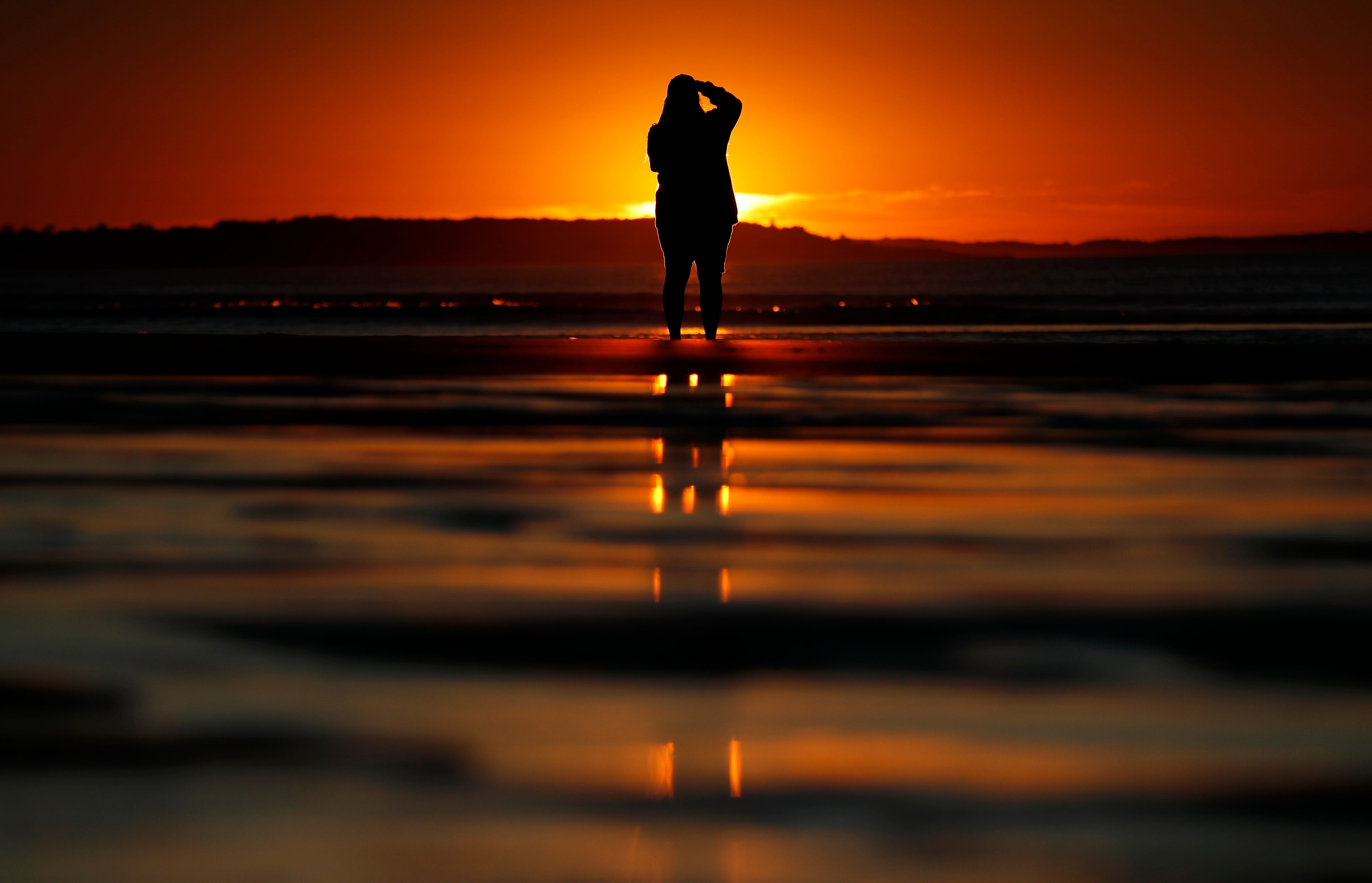Consuello Jessop, of Providence, R.I., photographs the sunrise at Ocean Park in Old Orchard Beach, Maine.