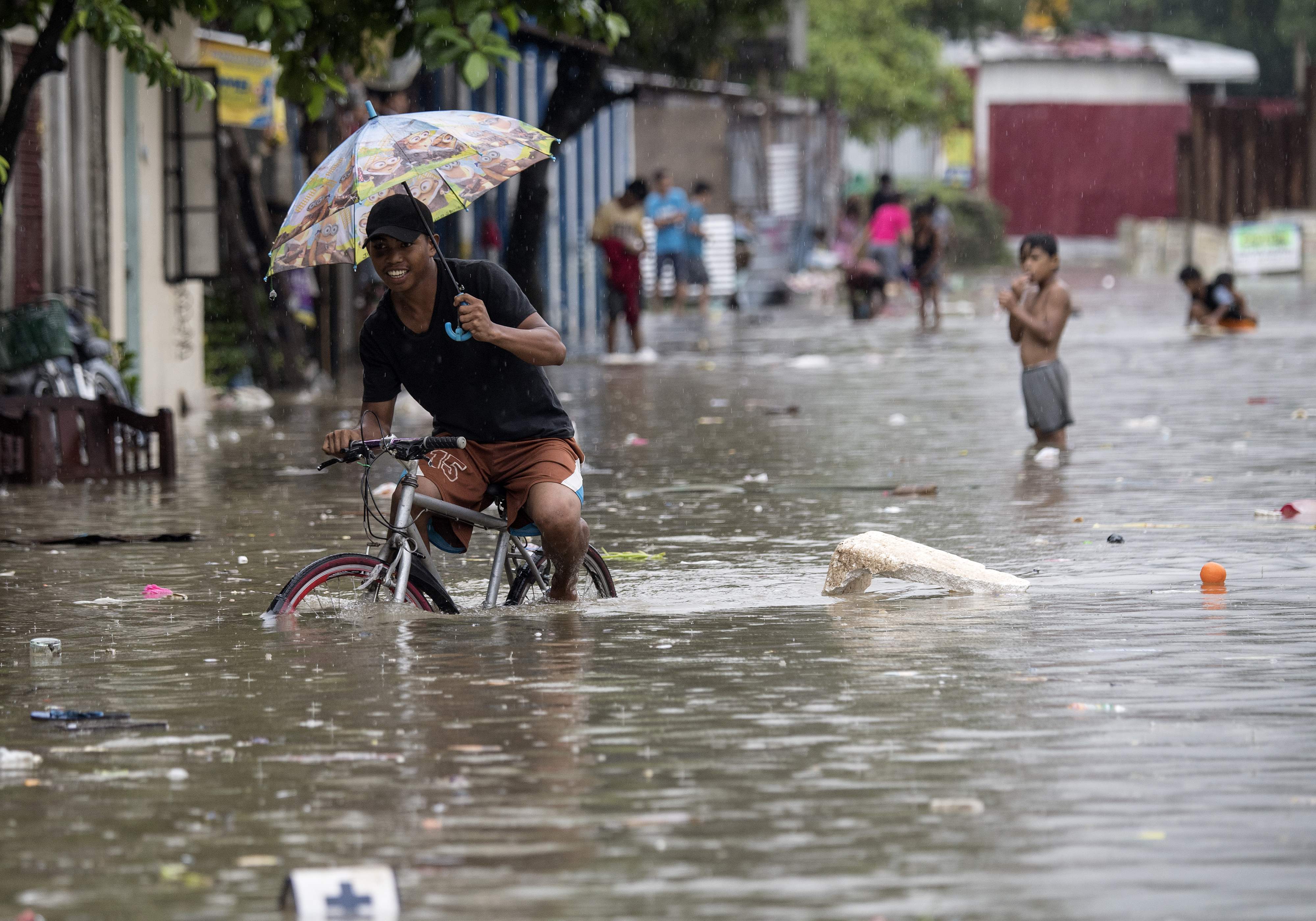 A man pedals his bicycle through a flooded street due to continuous rains caused by tropical depression Josie in Marikina, east of Manila on July 22, 2018.
