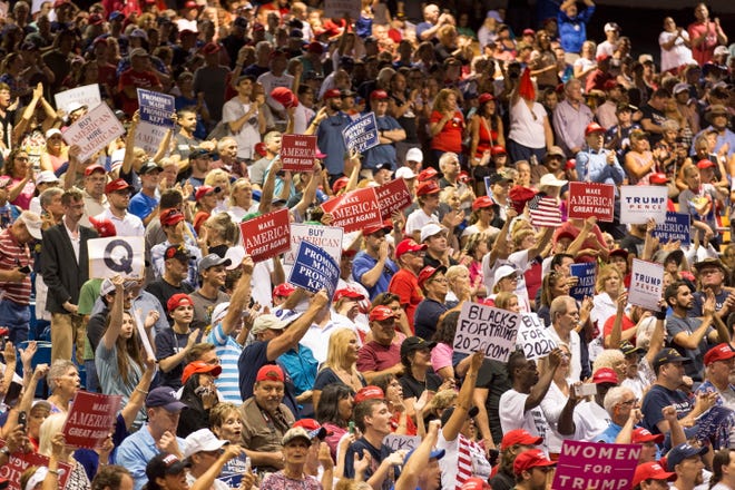 People cheer as President Donald Trump speaks at the Florida State Fairgrounds Expo Hall in Tampa, Florida on July 31. A sign showing the letter Q can be seen. Q stands for QAnon.