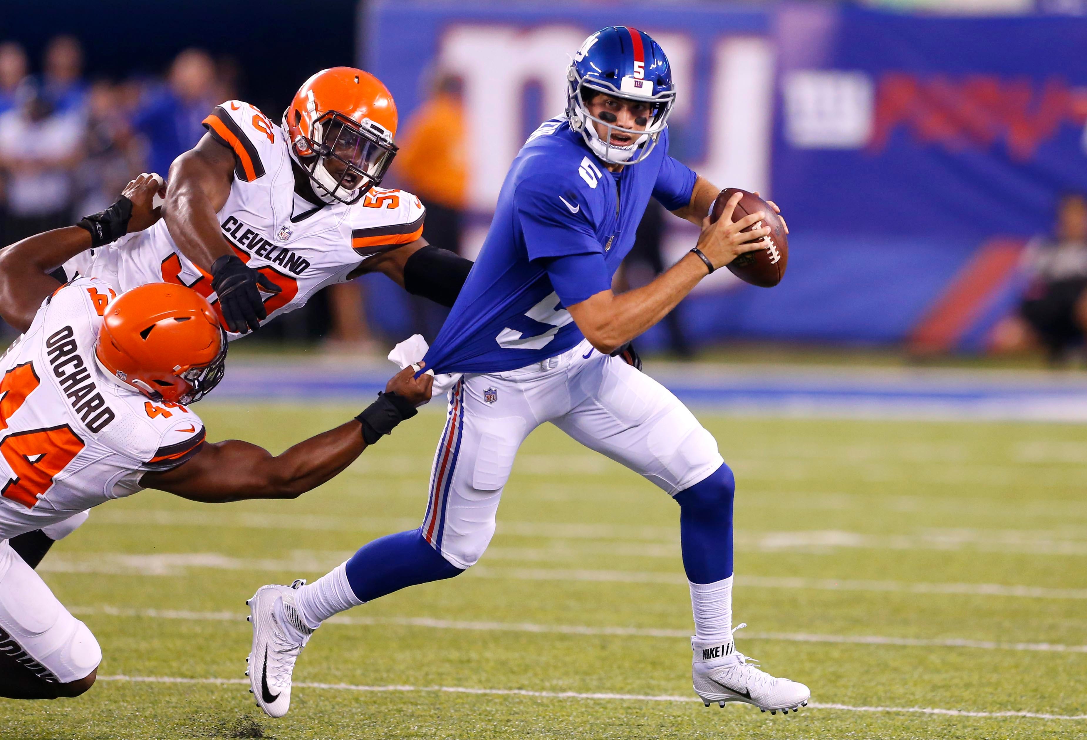 New York Giants quarterback Davis Webb runs from Cleveland Browns defensive end Nate Orchard and defensive end Chris Smith during first half at MetLife Stadium in East Rutherford, N.J.