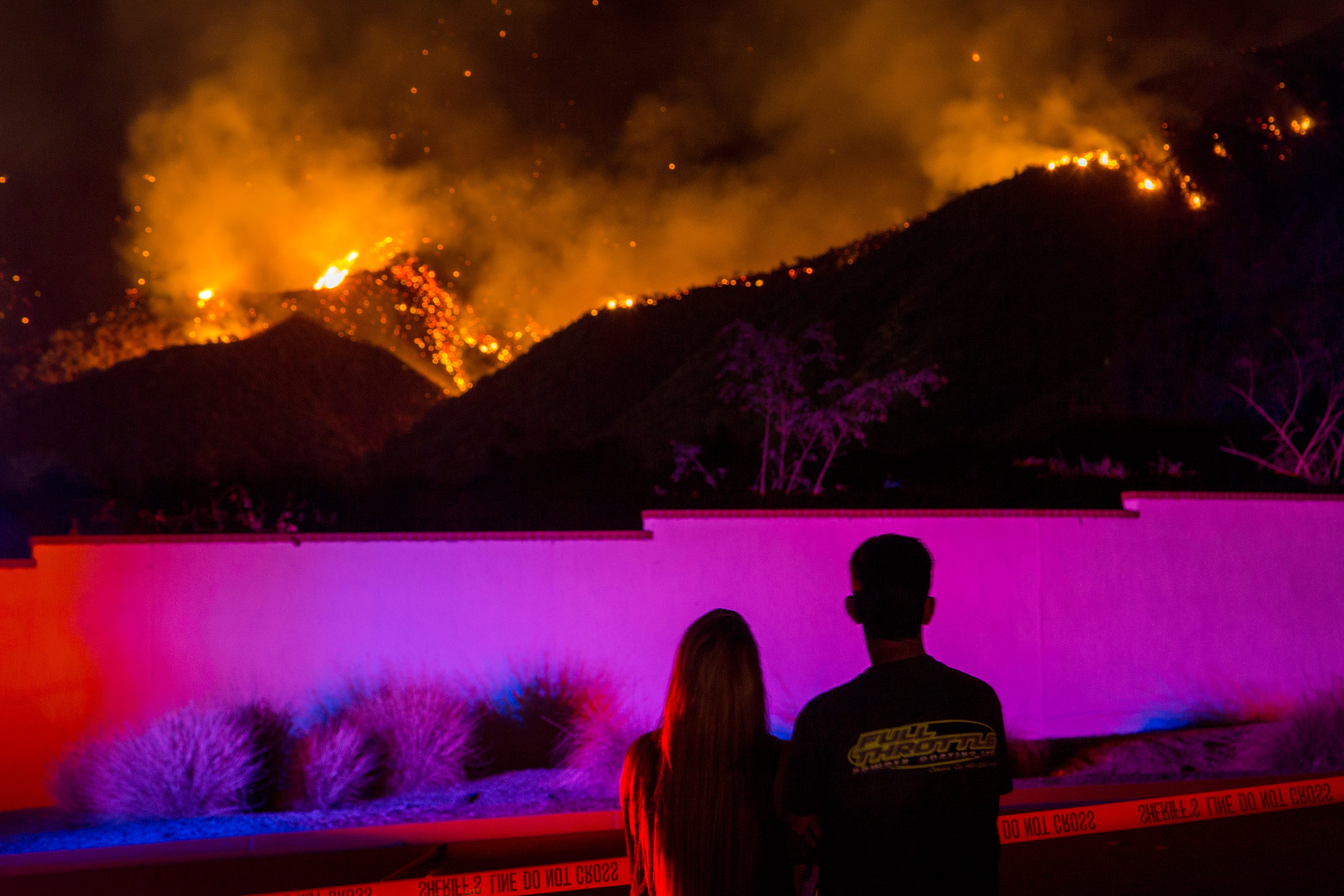 People watch flames near Glen Ivy Hot Springs resort during the Holy Fire in Corona, Calif., Aug. 10, 2018.