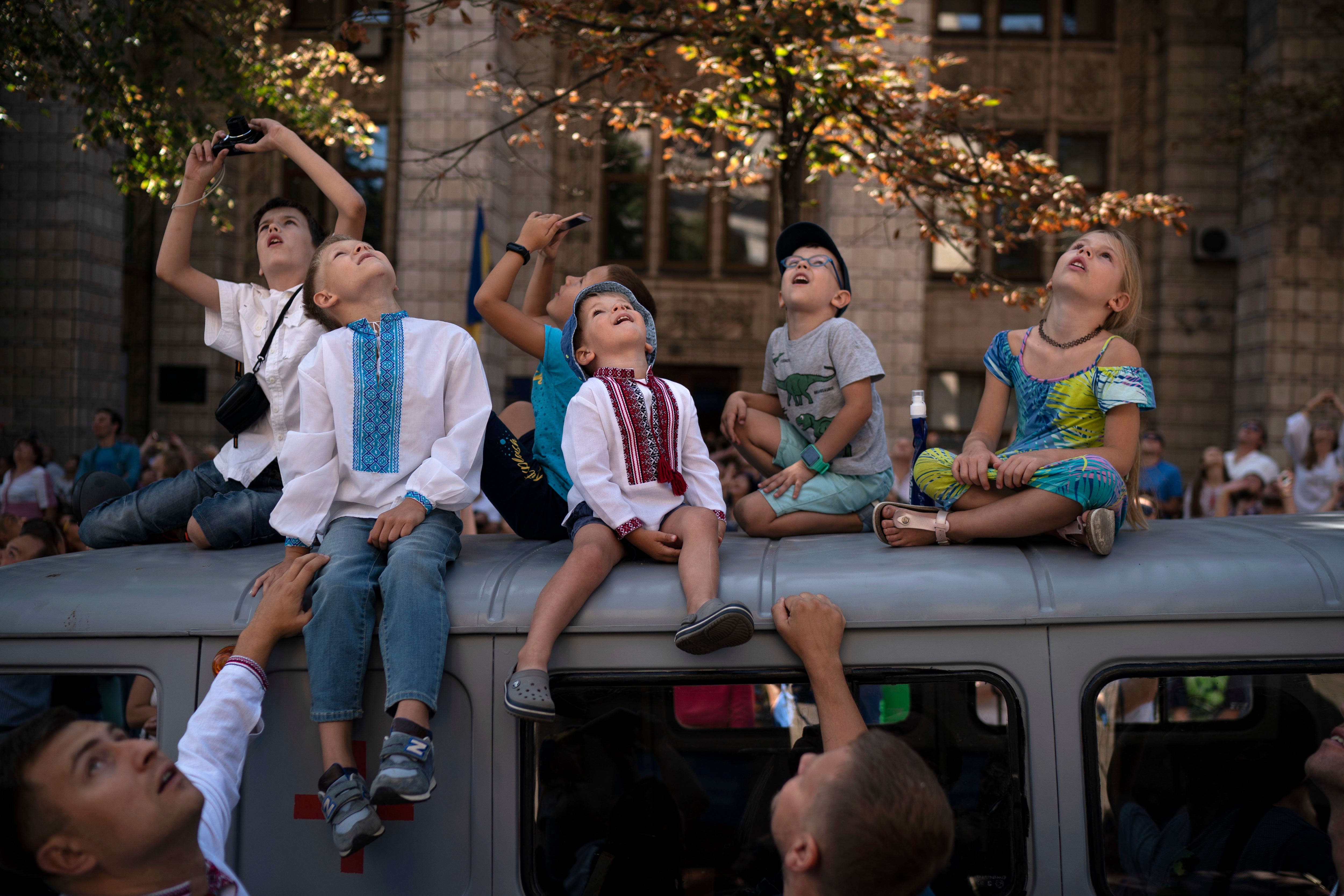 Children look up as military aircrafts fly above the city center during a military parade to celebrate Independence Day in Kiev, Ukraine.