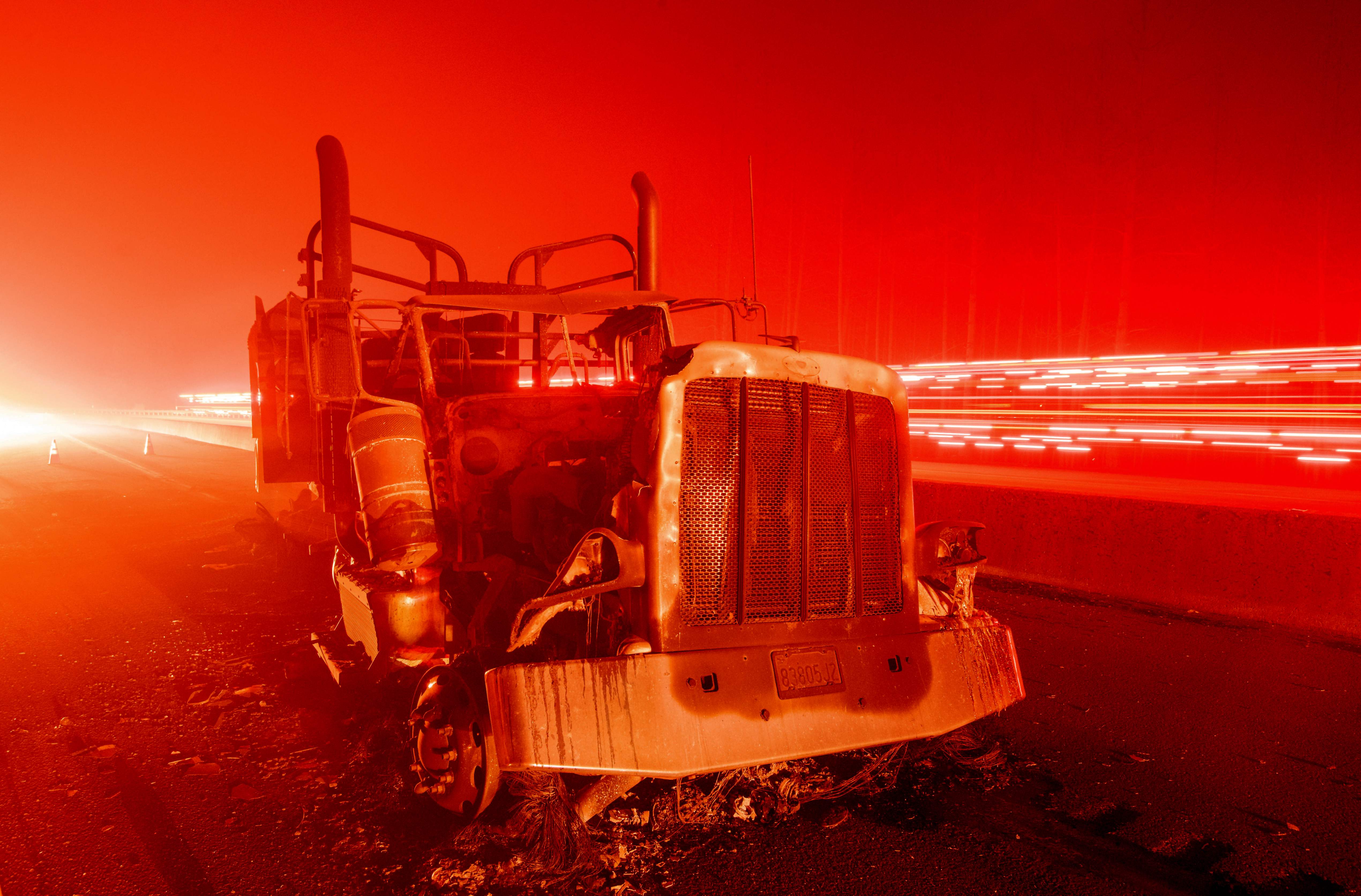 A fire vehicle passes by an abandoned burned out truck along Interstate 5 after the Delta Fire tore through the region and jumped the road in Delta, Calif. on Sept. 5, 2018.
