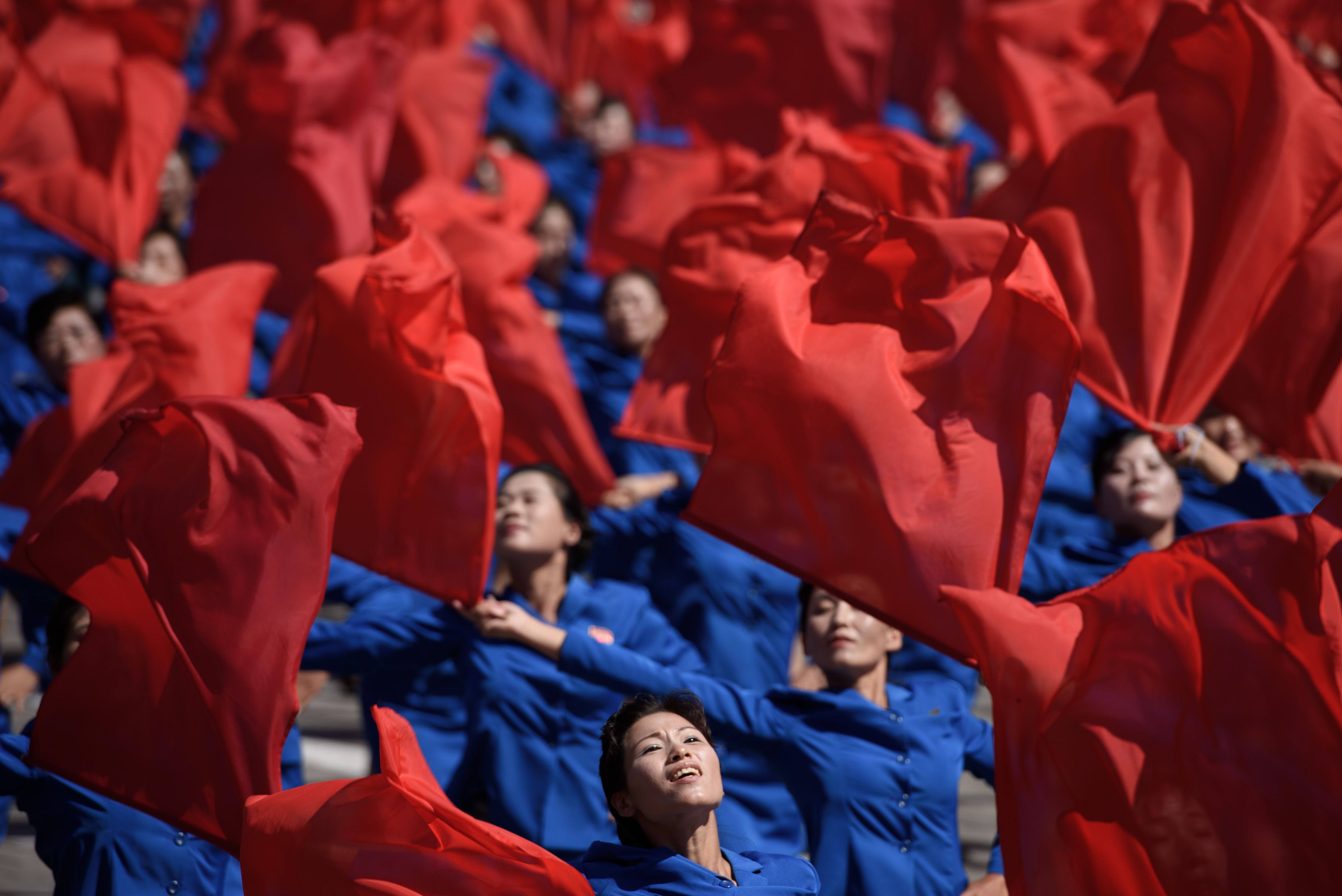Participants wave flags as they march past a balcony from where North Korea's leader Kim Jong Un was watching, during a mass rally on Kim Il Sung square in Pyongyang on Sept. 9, 2018.  North Korea held a military parade to mark its 70th birthday, but