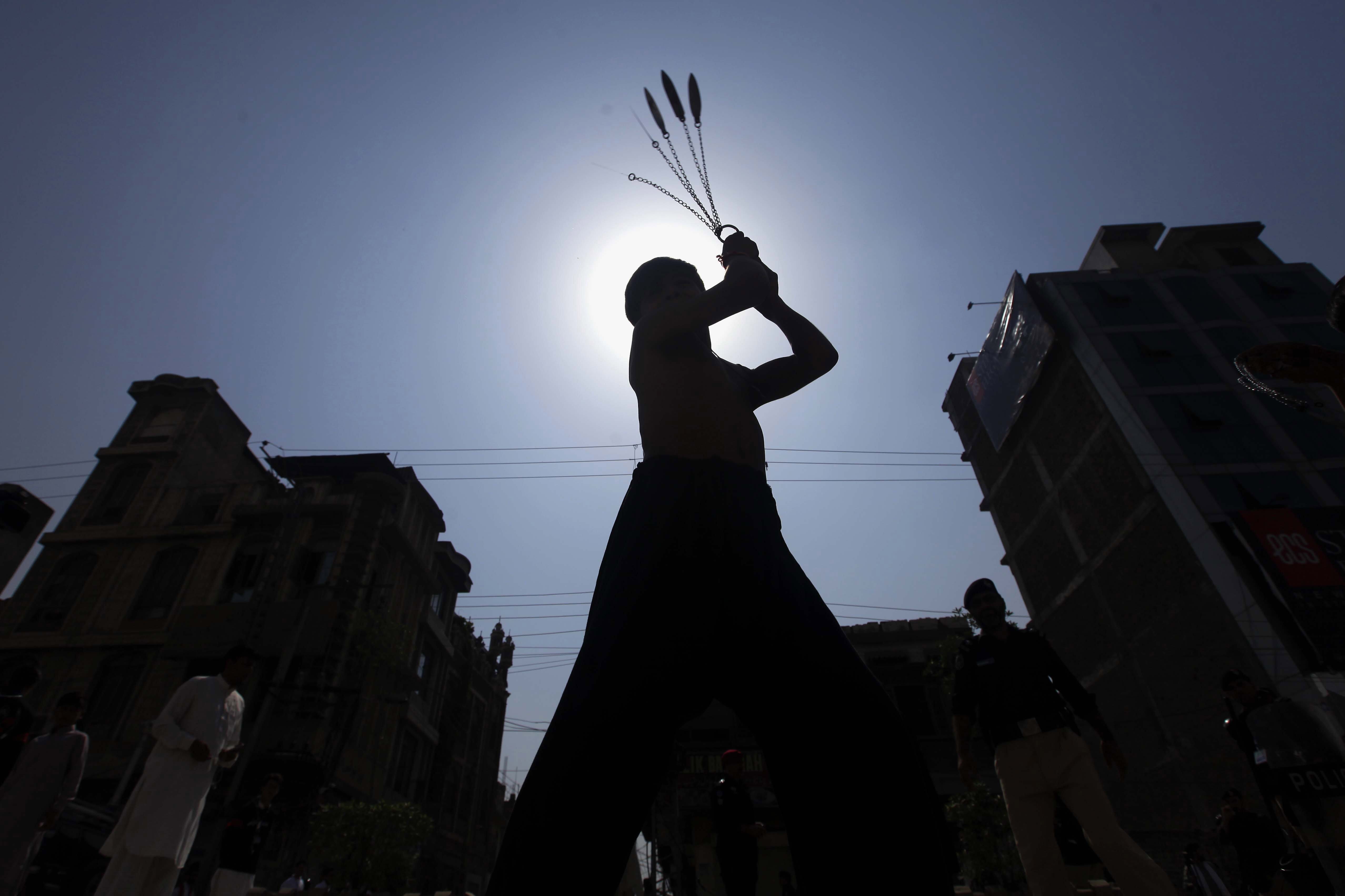 A Pakistani Shiite Muslim boy is silhouetted against the sky as he flagellates himself with chains and blades a mourning procession on the sacred month of Muharram, the first month of the Islamic Calendar, in Peshawar, Pakistan.