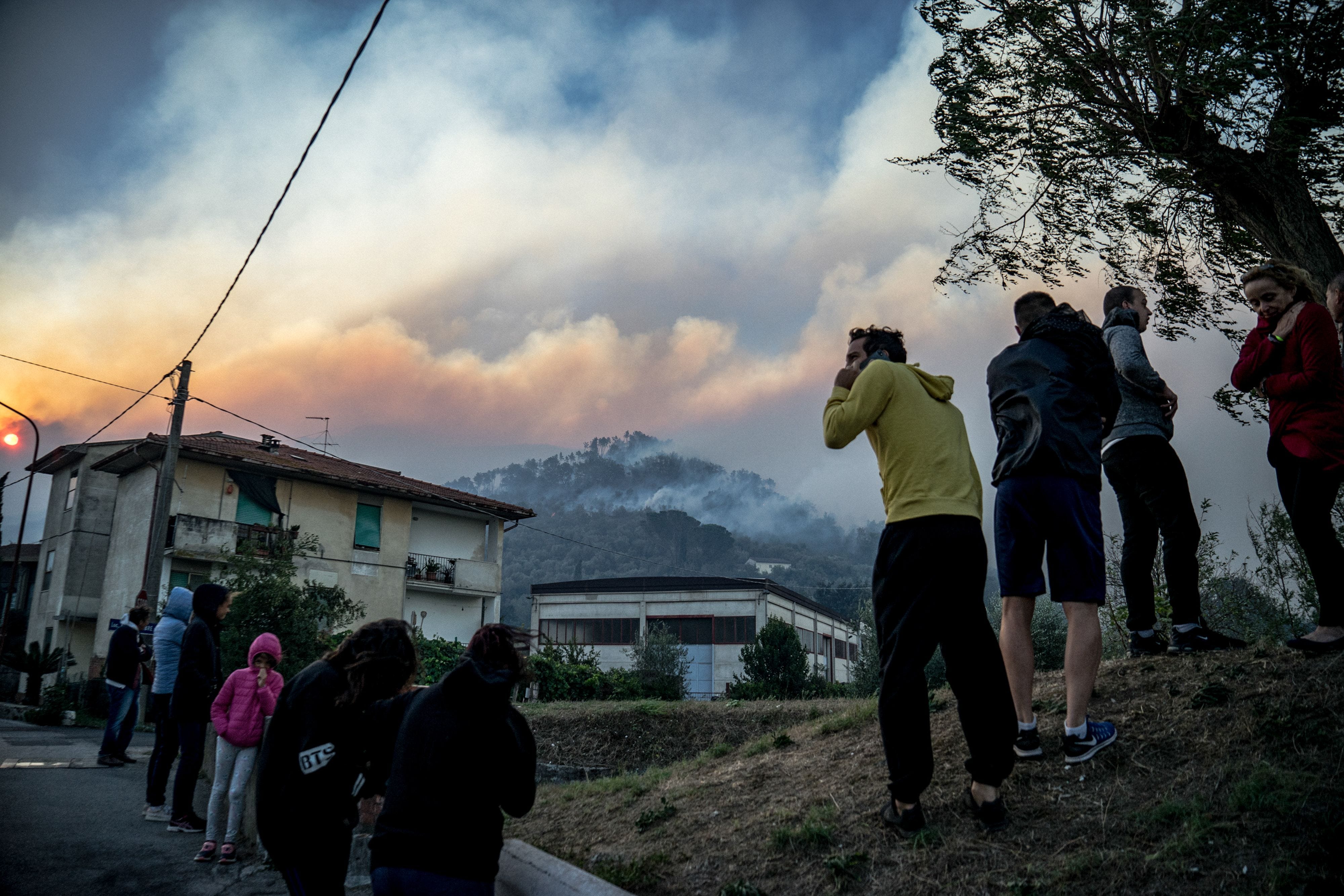 Inhabitants look at the fire on the nearby hills in Calci, near Pisa in the Tuscany region of Italy on Sept. 25, 2018.  A very extended fire is burning in the hills north of Pisa. Hundreds had to leave their home during the night.