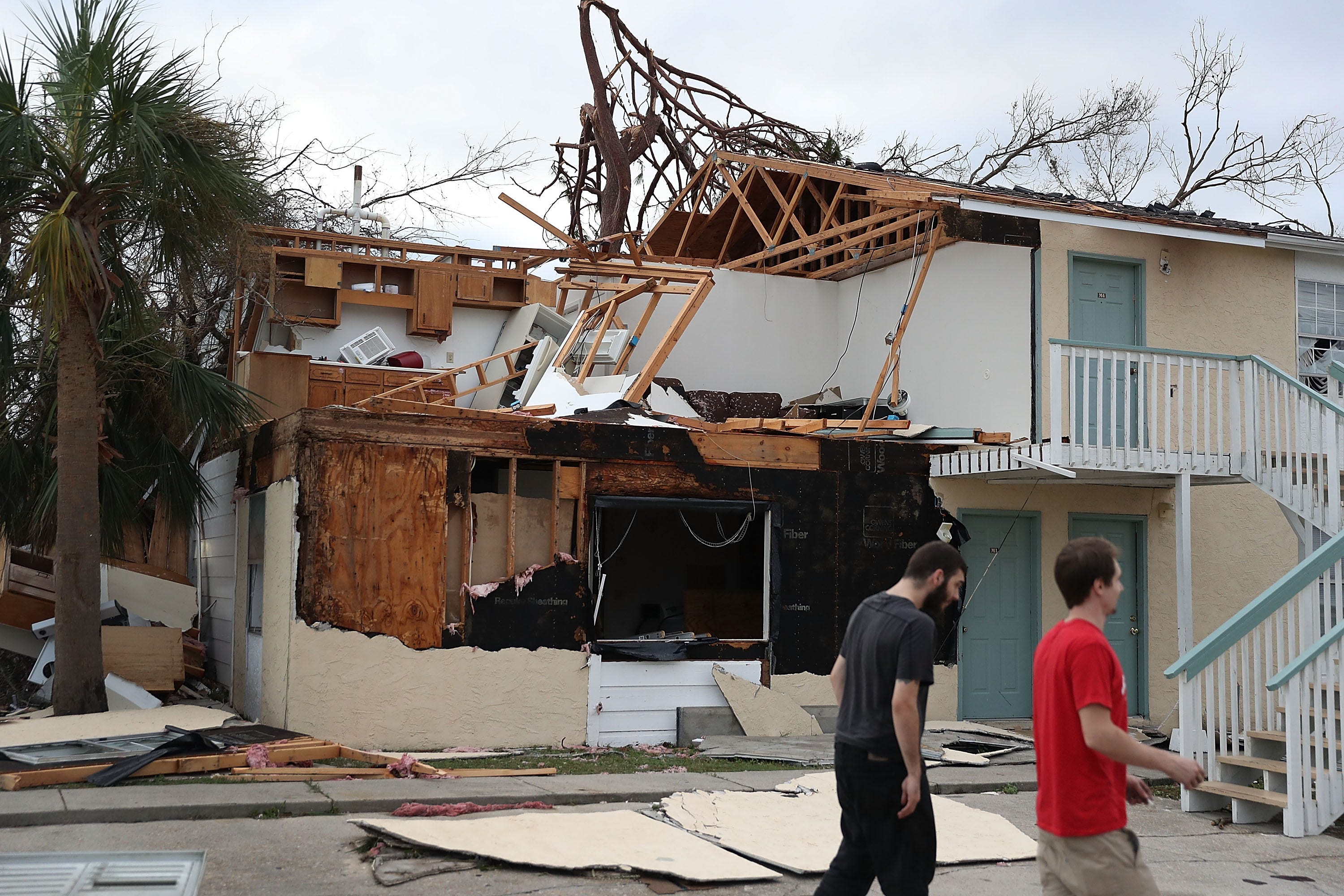 PANAMA CITY, FL - OCTOBER 11:  People walk past an apartment destroyed by Hurricane Michael on October 11, 2018 in Panama City, Florida. The hurricane hit the Florida Panhandle as a category 4 storm.  (Photo by Joe Raedle/Getty Images) ORG XMIT: 775241167 ORIG FILE ID: 1051884006