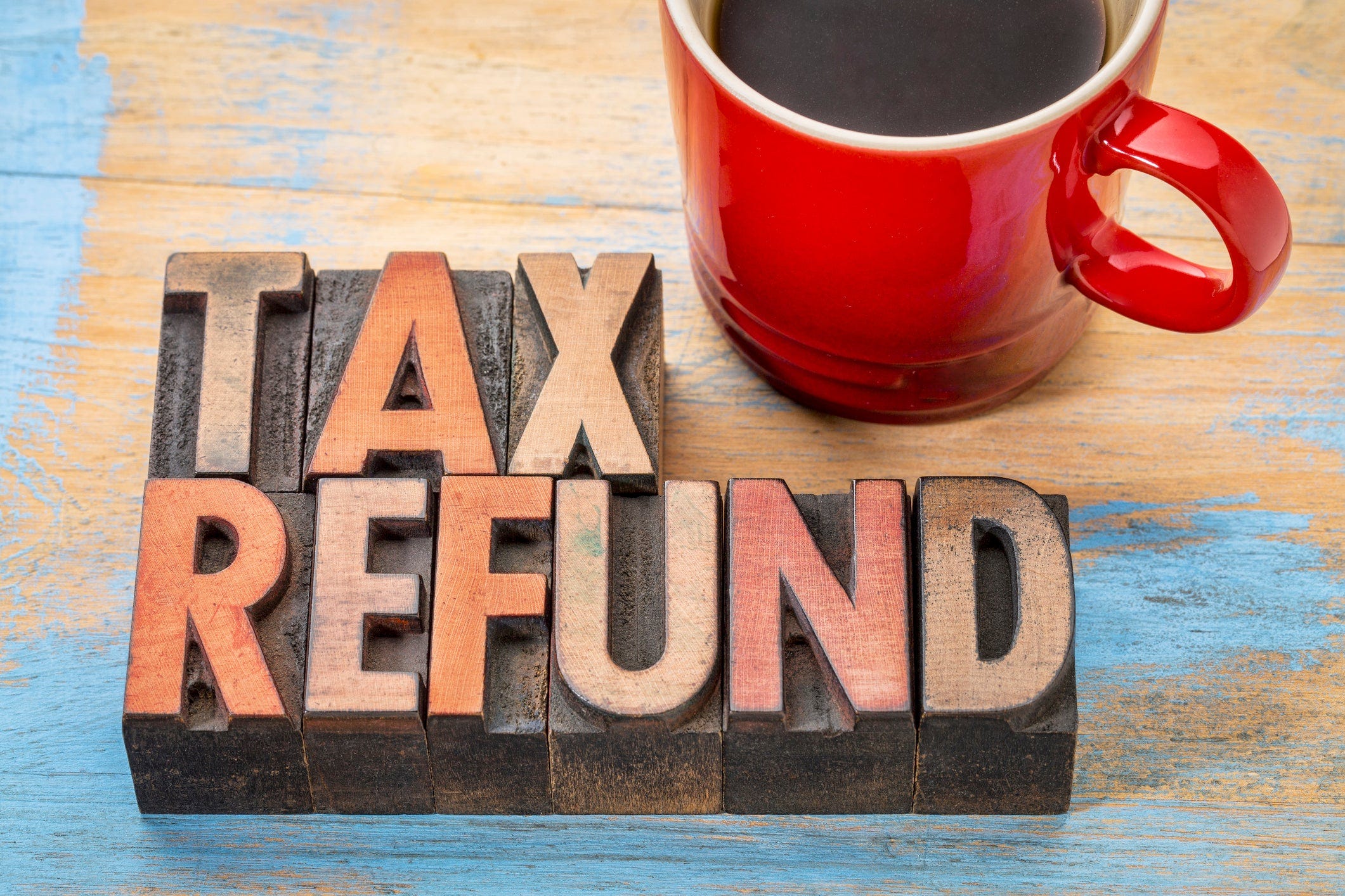 The words tax refund spelled out in block letters next to a red mug