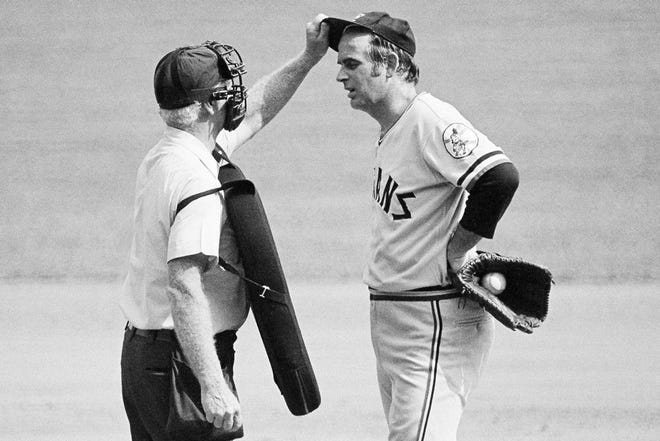 FILE - In this Sept. 3, 1973, file photo, home plate umpire John Flaherty checks Cleveland Indians pitcher Gaylord Perry's cap for an illegal substance, at the request of Milwaukee Brewers manager Del Crandall, during the first baseball game of a doubleheader in Milwaukee. Major league pitchers have been tinkering with the ball for years in search of an advantage, occasionally breaking major league rules in the process. But they might have to work a little harder on their deception this summer. (AP Photo/File)