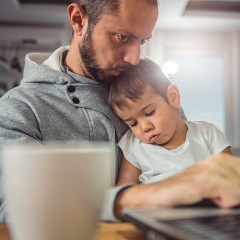 father working from home on laptop and kissing tod