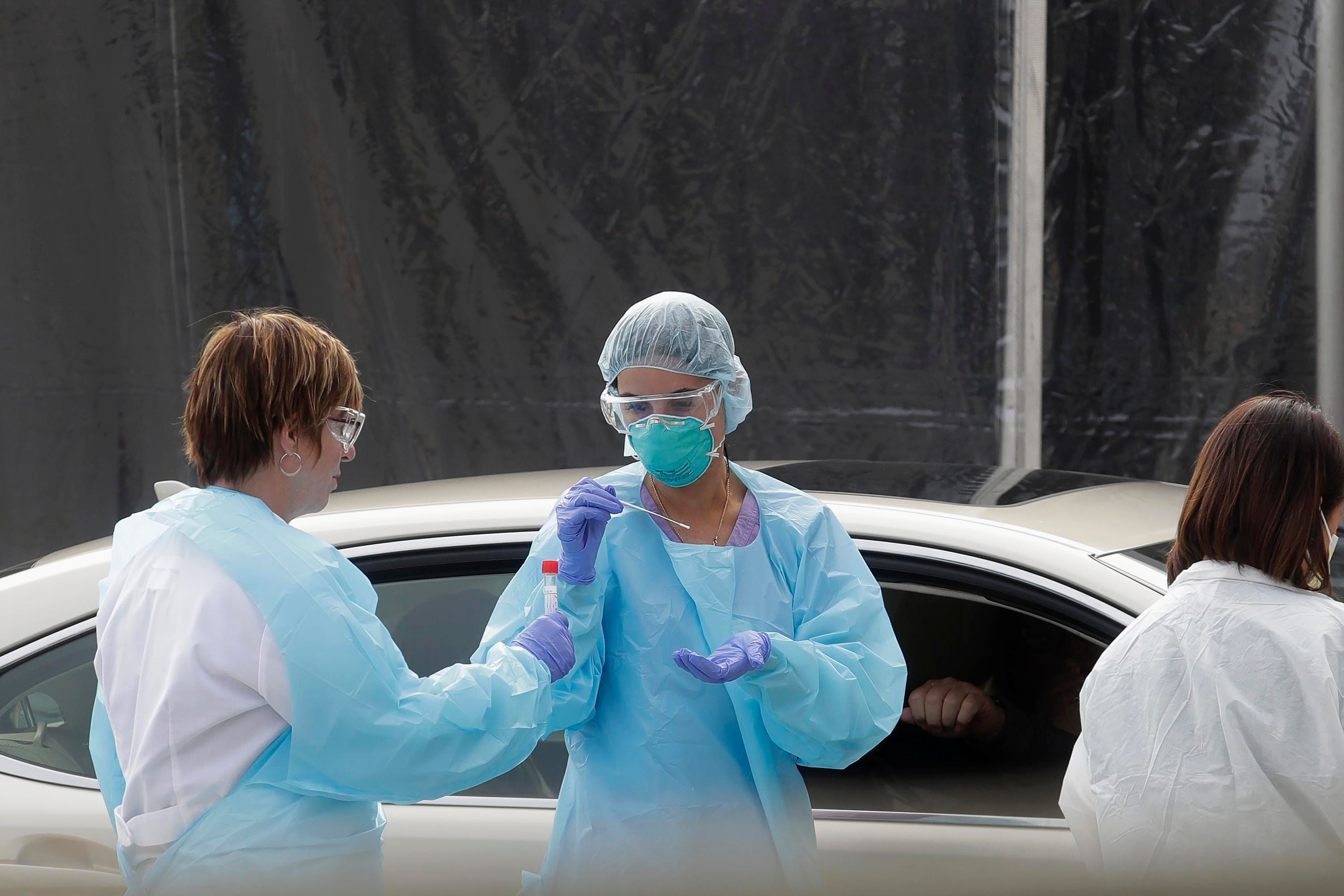 Health care personnel test a person in the passenger seat of a car for coronavirus at a Kaiser Permanente medical center parking lot in San Francisco.