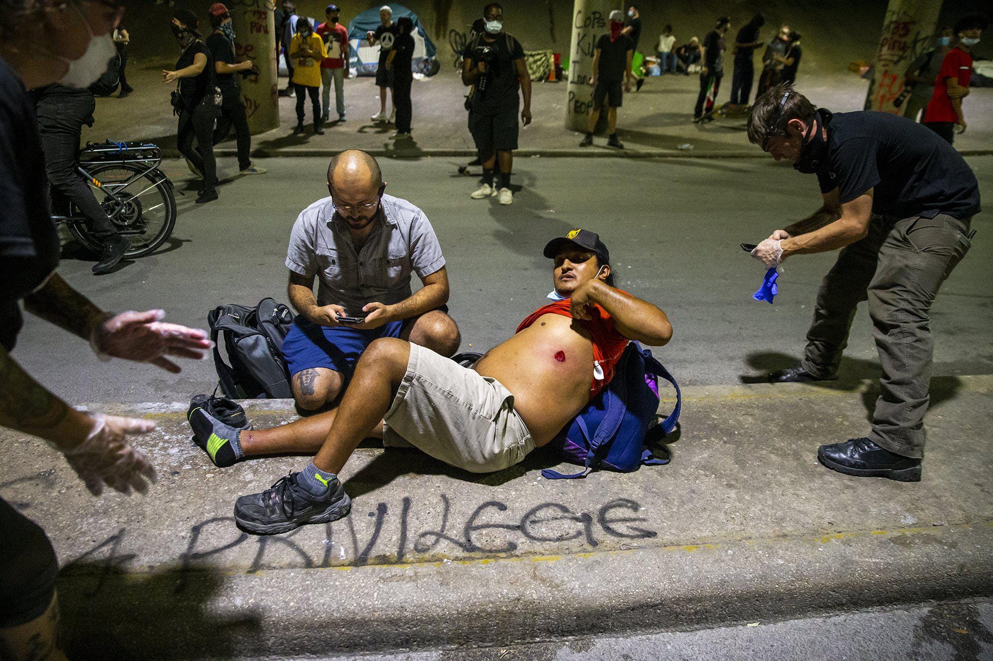 People help a protester after he was shot with a rubber bullet under Interstate 35 freeway in Austin Texas.  Demonstrators protest over the police killing of George Floyd  Saturday, May 30, 2020.