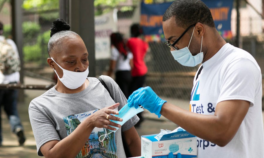 Stephane Labossiere, right, with the Mayor's Office of Immigrant Affairs, hands out masks and printed information about free coronavirus testing in Brooklyn offered by NYC Health + Hospitals in New York.