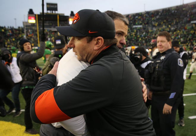 Oregon coach Mario Cristobal, left, and Oregon State coach Jonathan Smith embrace at midfield after the Ducks beat the Beavers 24-10 in last year's game.