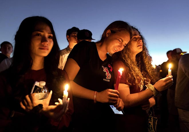 People attend a candlelit memorial service for victims a day after the mass shooting at Marjory Stoneman Douglas High School in Parkland that killed 17 people in February 2018.