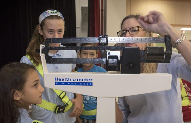 Palm Beach Public School nurse Diane King (far right) works with fifth-grade students in 2017 to weigh boxes of non-perishable food items for the Food for Families food drive.