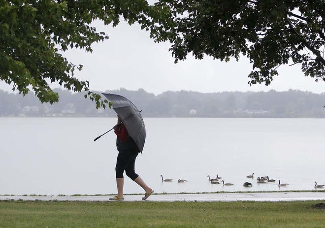 A pedestrian walks on the Spartan Trail along Springfield Lake Tuesday, Aug. 4, 2020 in Springfield Township, Ohio. Lakemore, Springfield Township, the Ohio EPA and Summit County are meeting on how to fix the lake, which has algae and bacteria contamination.