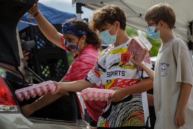 Left to right: Amber Bastin, Palm Beach Gardens, Kyle Fleisch, Wellington and Sean Labott Jr., West Palm Beach, place food in cars during the weekly Feeding South Florida food distribution event at Royal Palm Beach Commons Park in Royal Palm Beach, Fla., on Wednesday, August 10, 2020. As the pandemic continues, joblessness has created an ongoing need for foodstuffs in Palm Beach County.