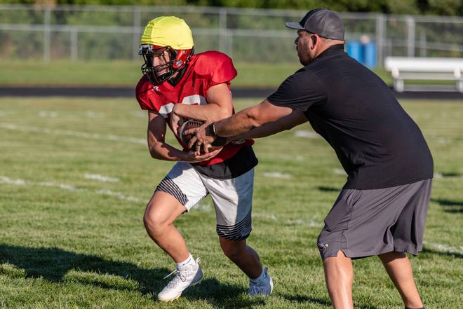 Southern Boone head coach Trent Tracy hands off the football to Jacob Bowles during a drill on Aug. 20.