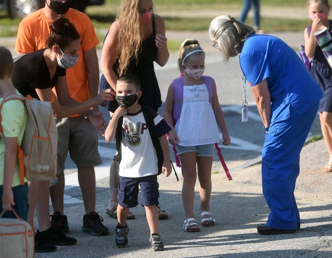 A parent helps secure a child's mask as a nurse greets children during Maple Street Magnet School's first day of school in August 2020.