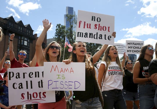 Maria Harvey and her sister Ashley Makridakis  protest mandatory flu vaccinations outside the Massachusetts Statehouse on Aug. 30 in Boston. Public health authorities say flu shots are very important this year to avoid overburdening the health system amid the coronavirus pandemic.