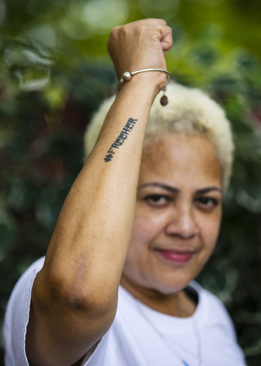 Stacey Borden raises her fist to show her tattoo that reads #FREEHER outside her Brockton home on Tuesday, Aug. 25, 2020. The #FreeHer campaign is part of The National Council's mission to end incarceration of women and girls.