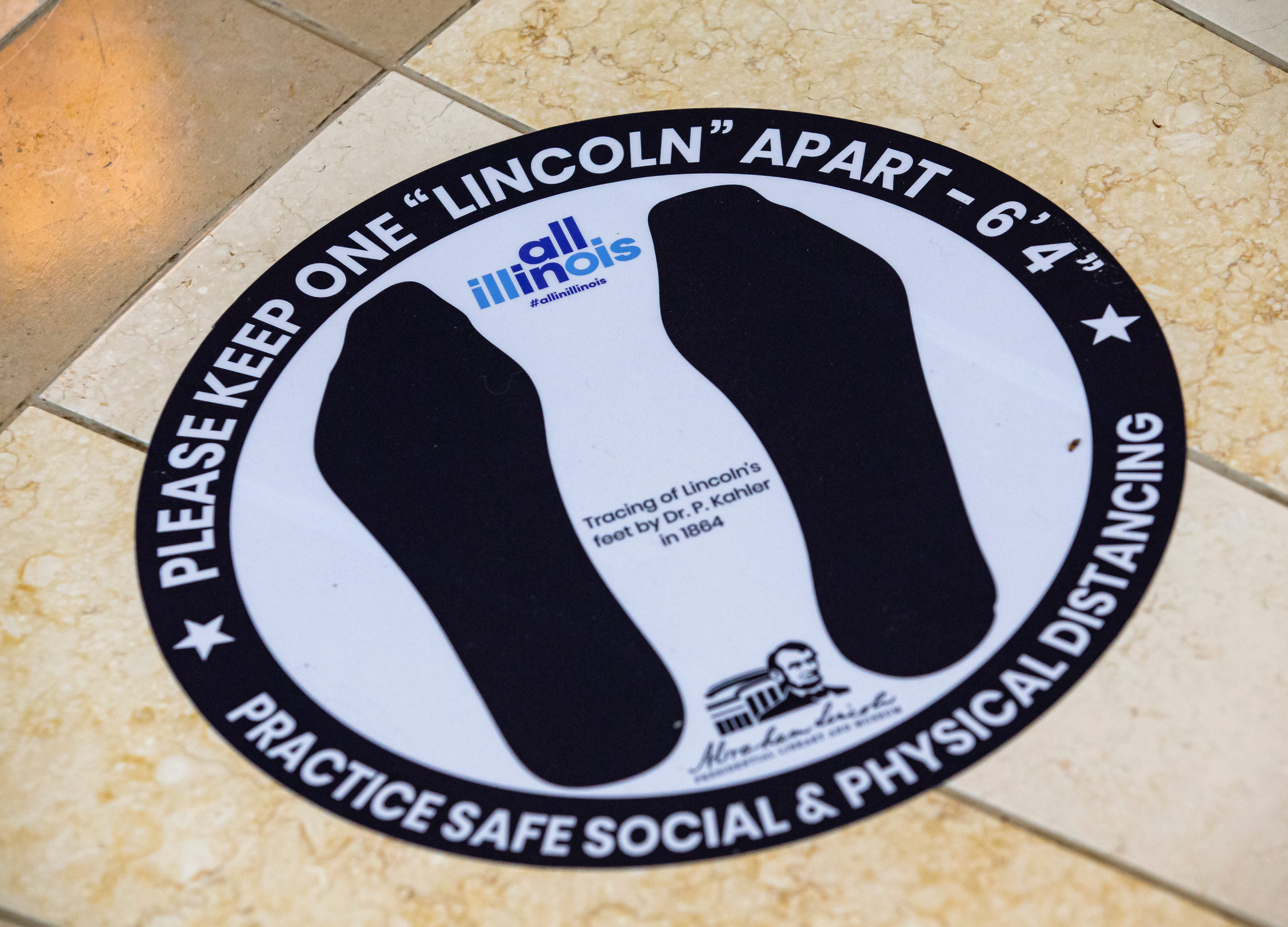 Signs along the floor encourage patrons to "Please Keep one Lincoln Apart - 6' 4" in a reference to Abraham Lincoln's height, for safe social distancing as the Abraham Lincoln Presidential Museum got set to reopen to the public during the COVID-19 pandemic, Tuesday, June 30, 2020, in Springfield, Ill.