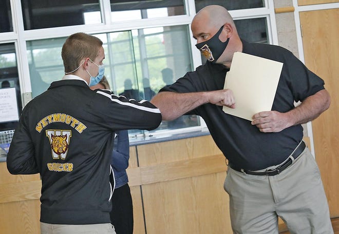 Sgt. Michael Chesna Memorial Scholarship recipient Matt Fuller, of Weymouth, gets a congratulatory elbow bump from Chesna Soccer Jamboree Director, Don Whitaker at the Weymouth Police Station on Monday.