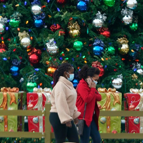 Shoppers wearing face masks pass by holiday decora