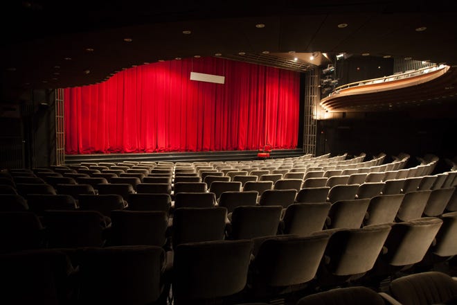 Empty theater with red curtain drawn across the stage