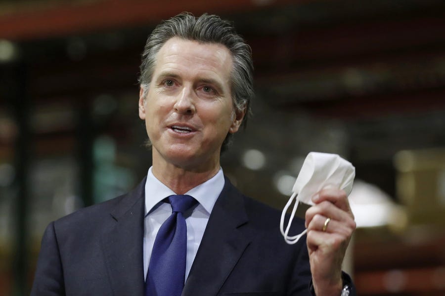 California Gov. Gavin Newsom holds a face mask during a news conference in Rancho Cordova, Calif.